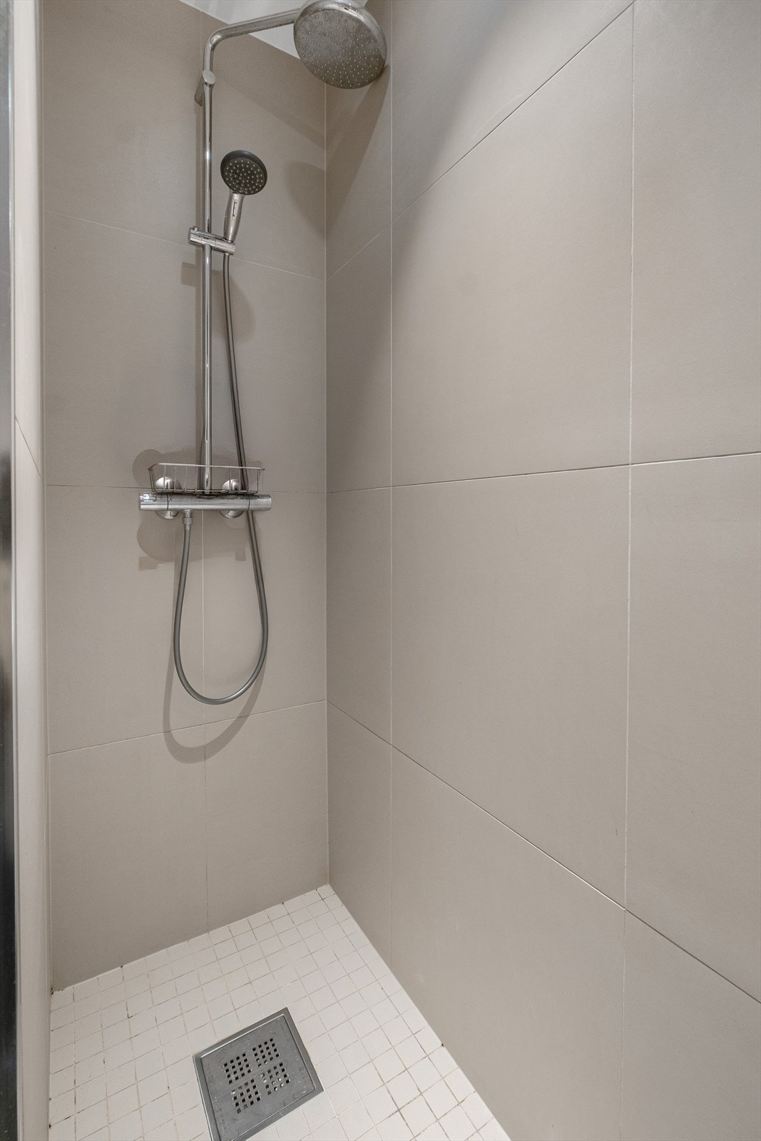 Badet er innredet med baderomsinnredning med nedfelt servant, speil med belysning og vegghengt toalett. Dusjen er plassert i hjørnet og har håndholdt dusjarmatur. Galleribilde