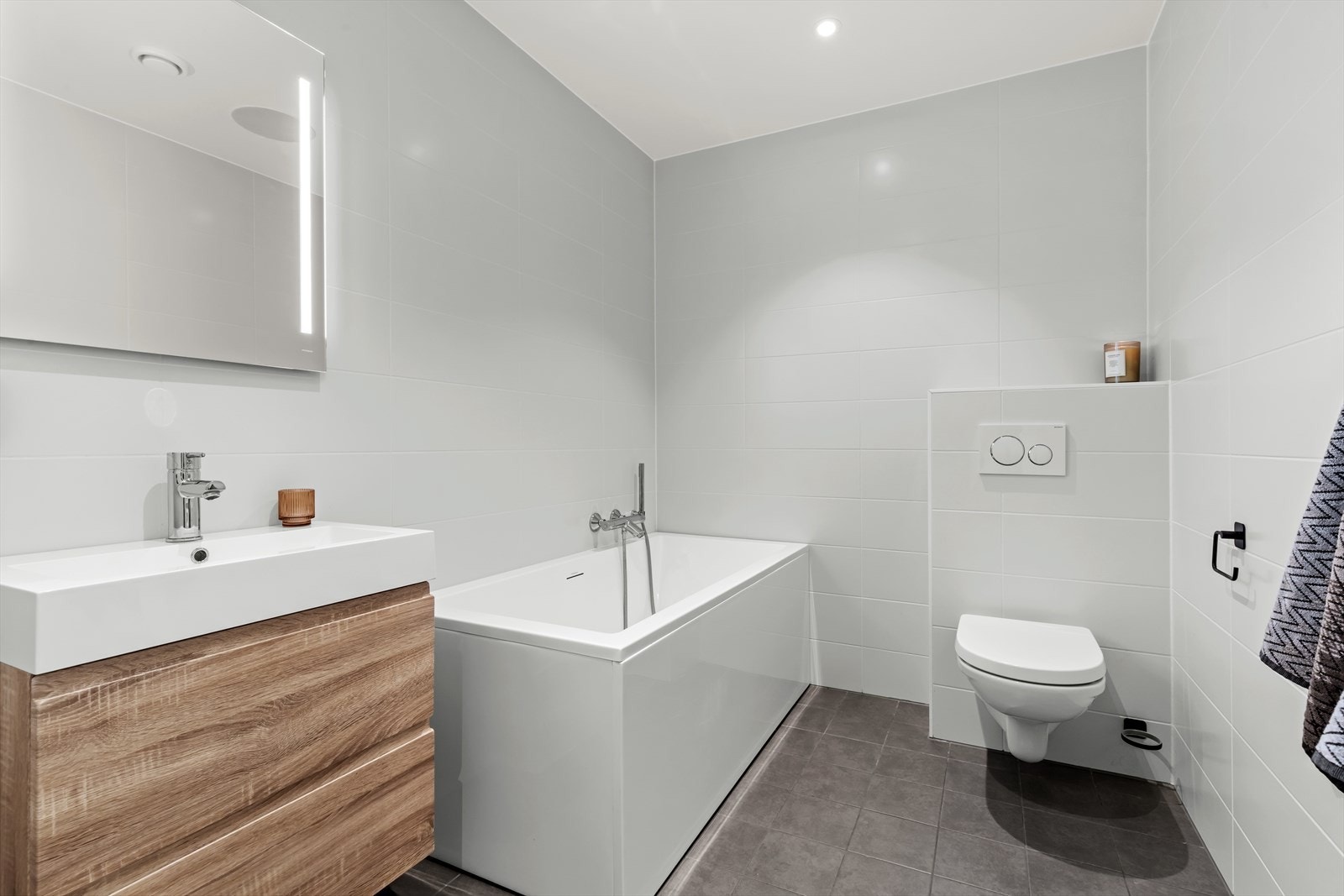 Bad/vaskerom med helfliset overflater, gulvvarme og downlights. Det er opplegg for vaskemaskin. Galleribilde