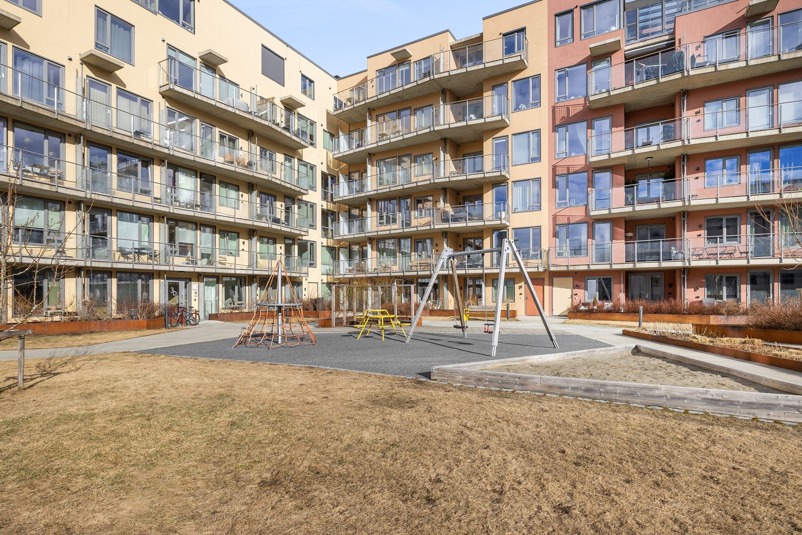 Fasadebilde. Godt etablert felles uteområde med benker, internstier og frodige vekster på sommerhalvåret. Galleribilde