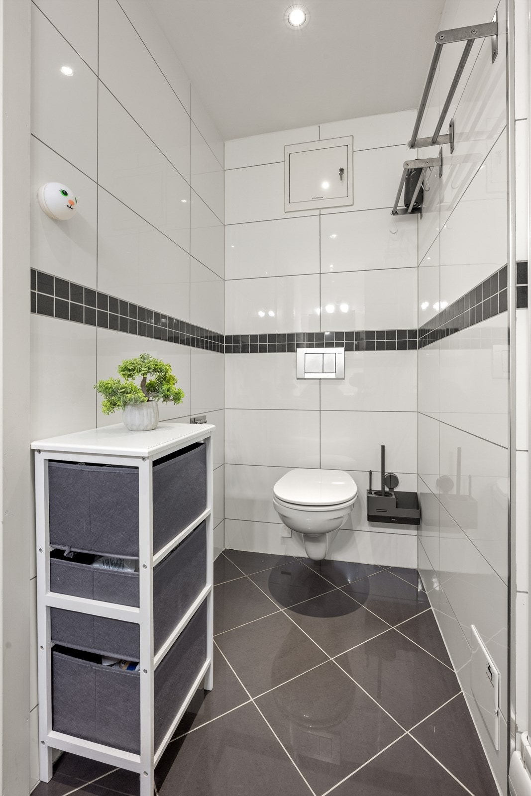 Badet har innredning med fronter i hvit høyglans med nedfelt servant, speil og belysning, veggmontert toalett og dusjkabinett. Galleribilde