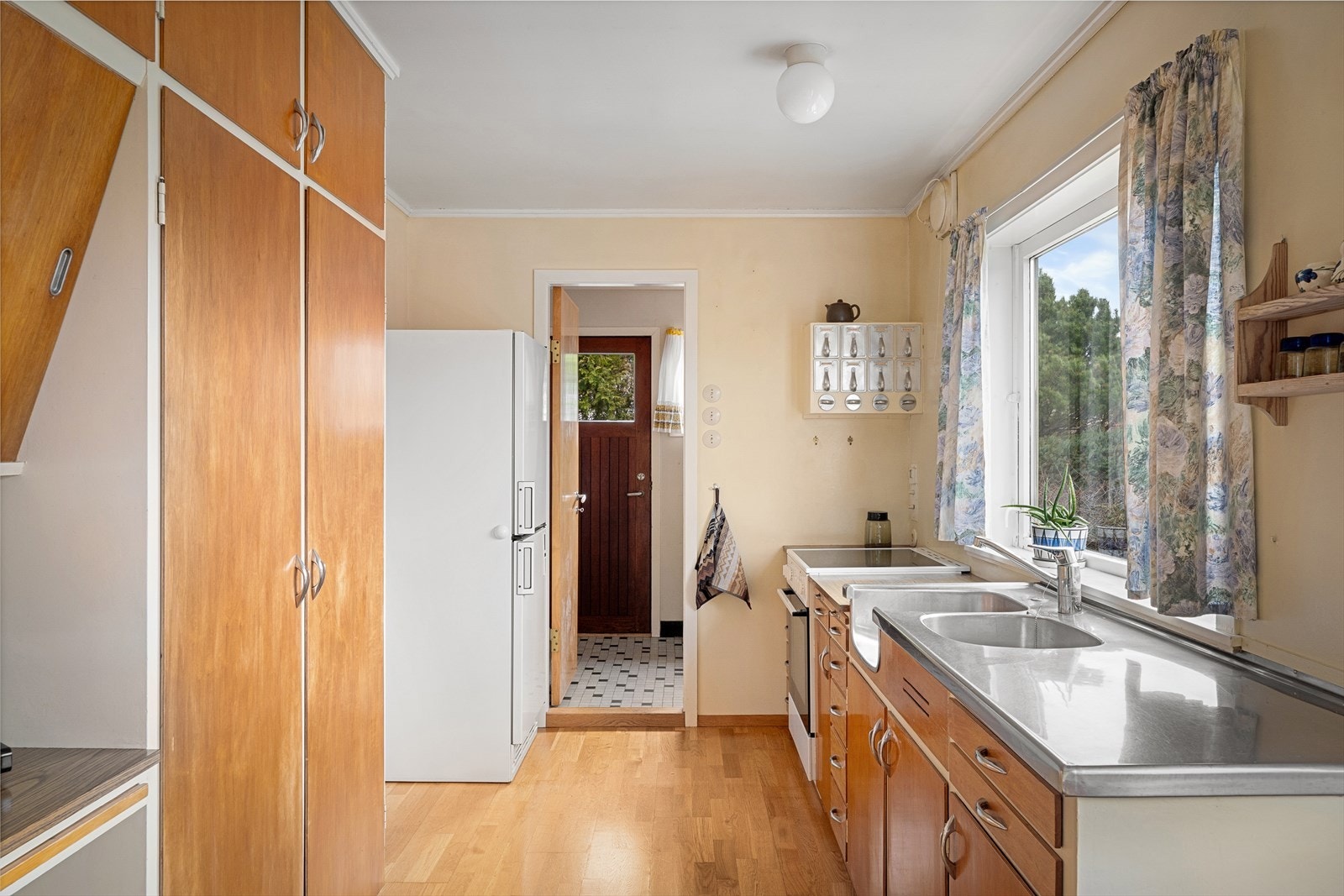 Et romslig stedbygget kjøkken med flotte trefronter og hvite rammer. Plass til frokostbord og store vinduer mot egen hage med mye naturlig lysinnslipp. Galleribilde