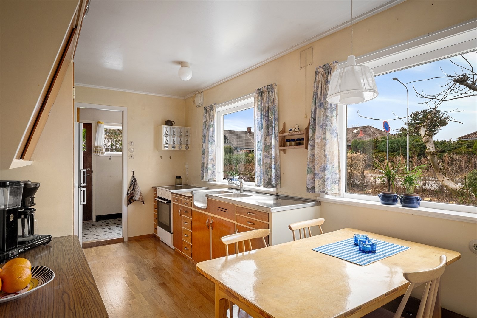 Et romslig stedbygget kjøkken med flotte trefronter og hvite rammer. Plass til frokostbord og store vinduer mot egen hage med mye naturlig lysinnslipp. Galleribilde