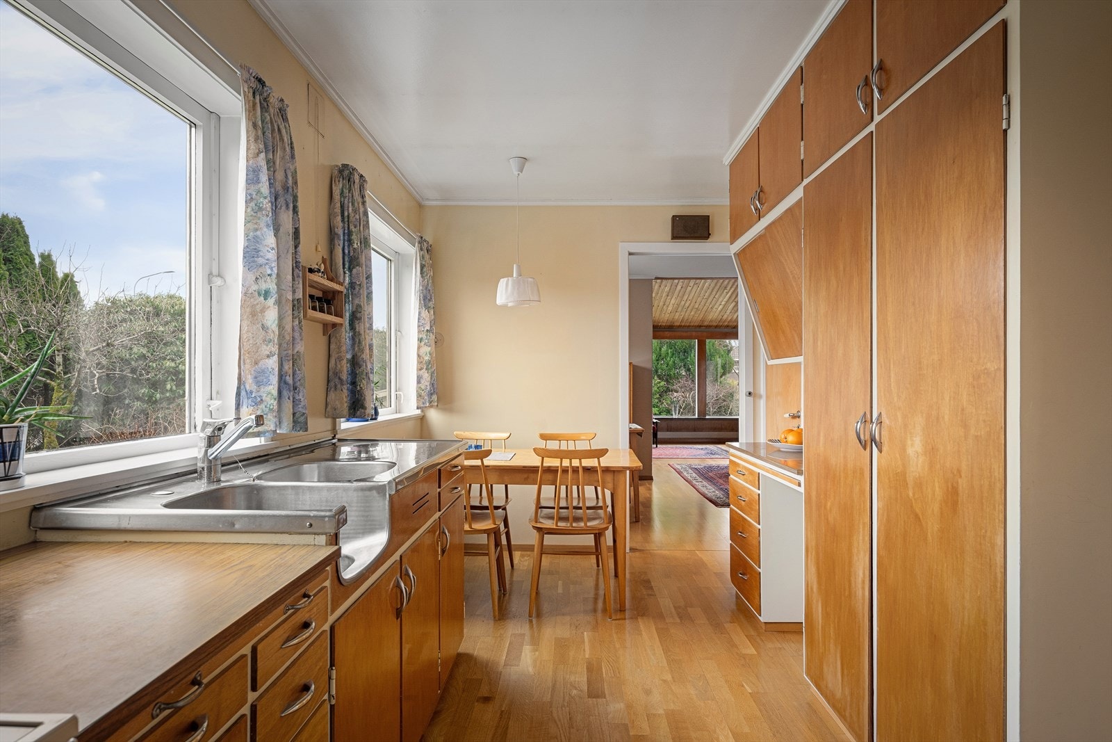 Et romslig stedbygget kjøkken med flotte trefronter og hvite rammer. Plass til frokostbord og store vinduer mot egen hage med mye naturlig lysinnslipp. Galleribilde