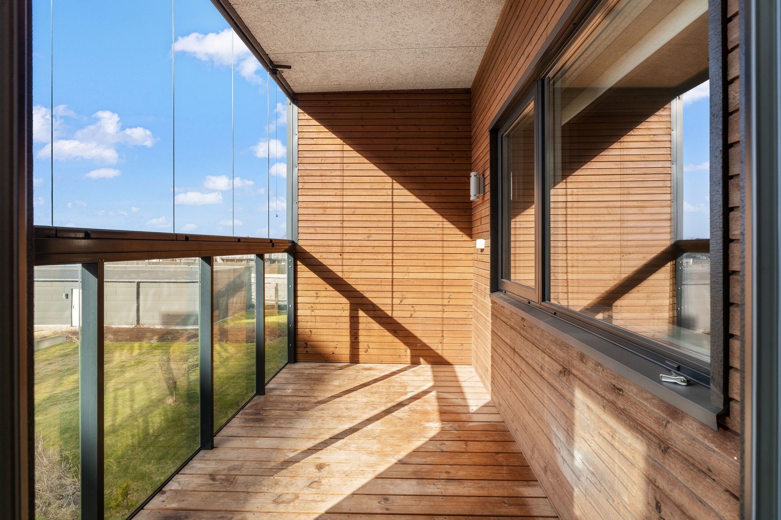 Balkonggulvet er belagt med terrassebord, og innglassingen gjør uteplassen anvendelig store deler av året. Galleribilde