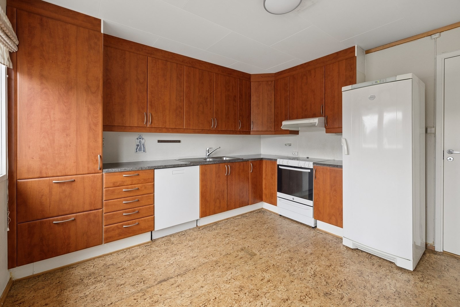 Det romslige, separate kjøkkenet byr på en innredning med glatte fronter i kirsebær utførelse, benkeplater i laminat, rustfri benkebeslag med oppvaskkum, ventilator og opplegg for oppvaskmaskin. Galleribilde