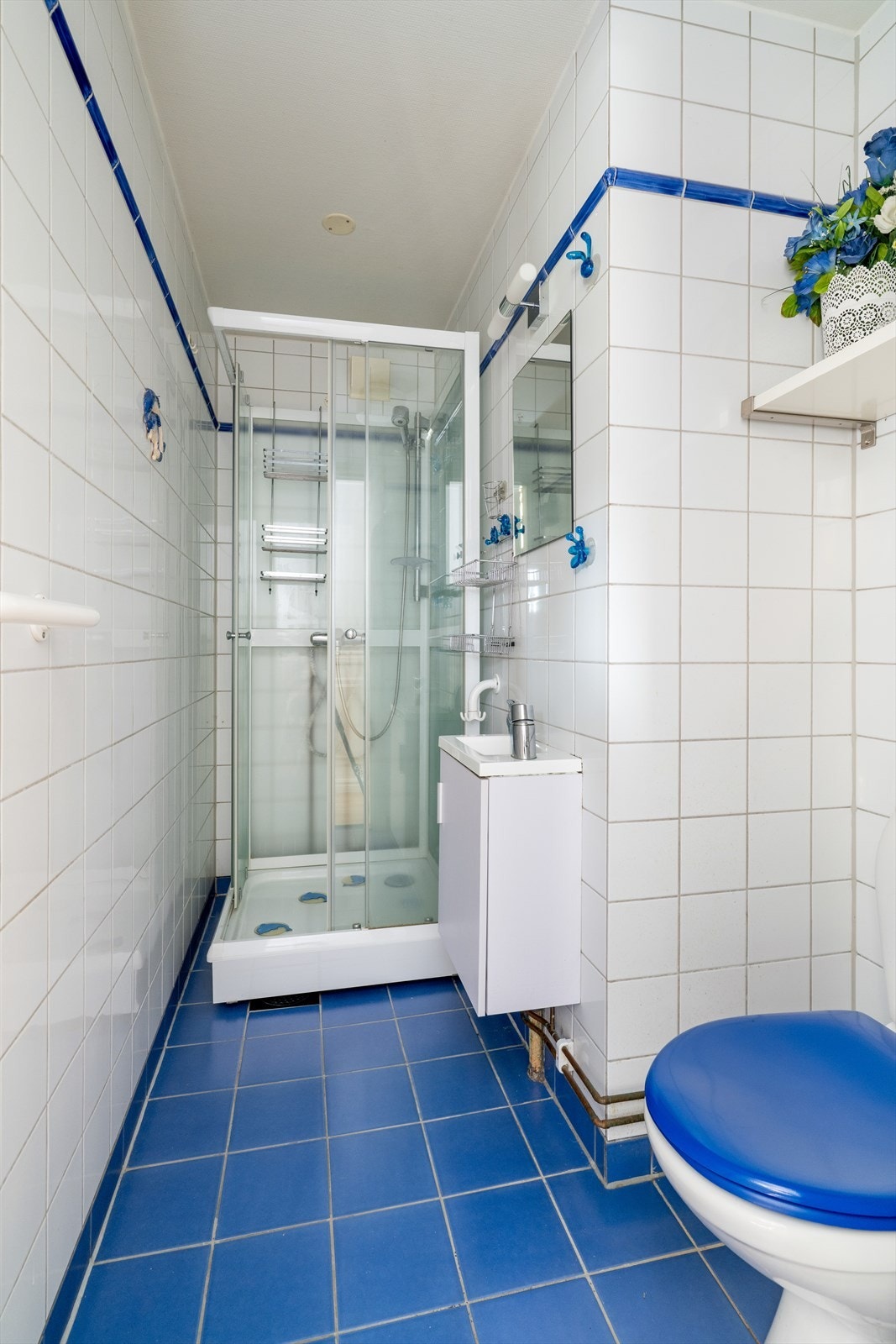 Eldre, flislagt bad ved entré med varmekabler i gulv. Dette badet er innredet med toalett, vegghengt servantskap og
dusjkabinett. Galleribilde