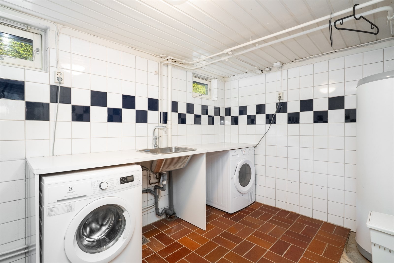 Eldre, flislagt vaskerom med varmekabler i gulv. Rommet er innredet med benkeplate og nedfelt utslagskum, samt opplegg for vaskemaskin og tørketrommel. Galleribilde