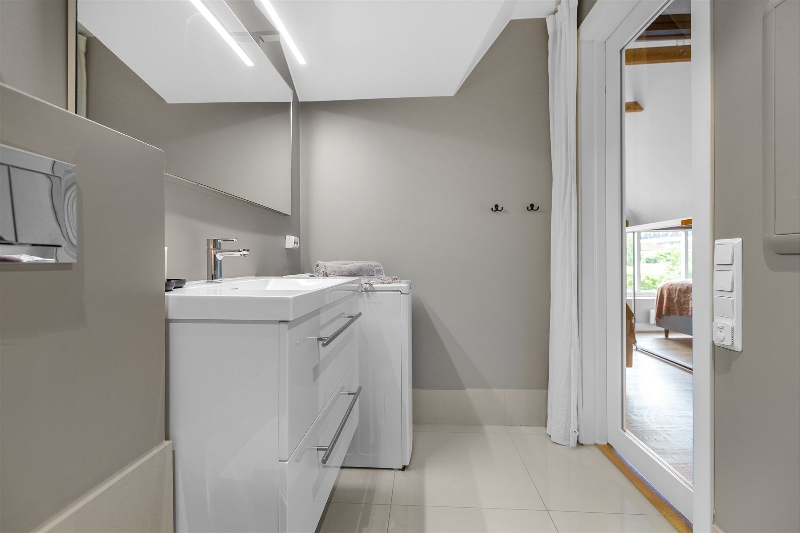 Badet har innredning med servant, speil, belysning, veggmontert toalett, dusjvegger/hjørne og opplegg for vaskemaskin. Det er elektriskstyrt vifte. Galleribilde