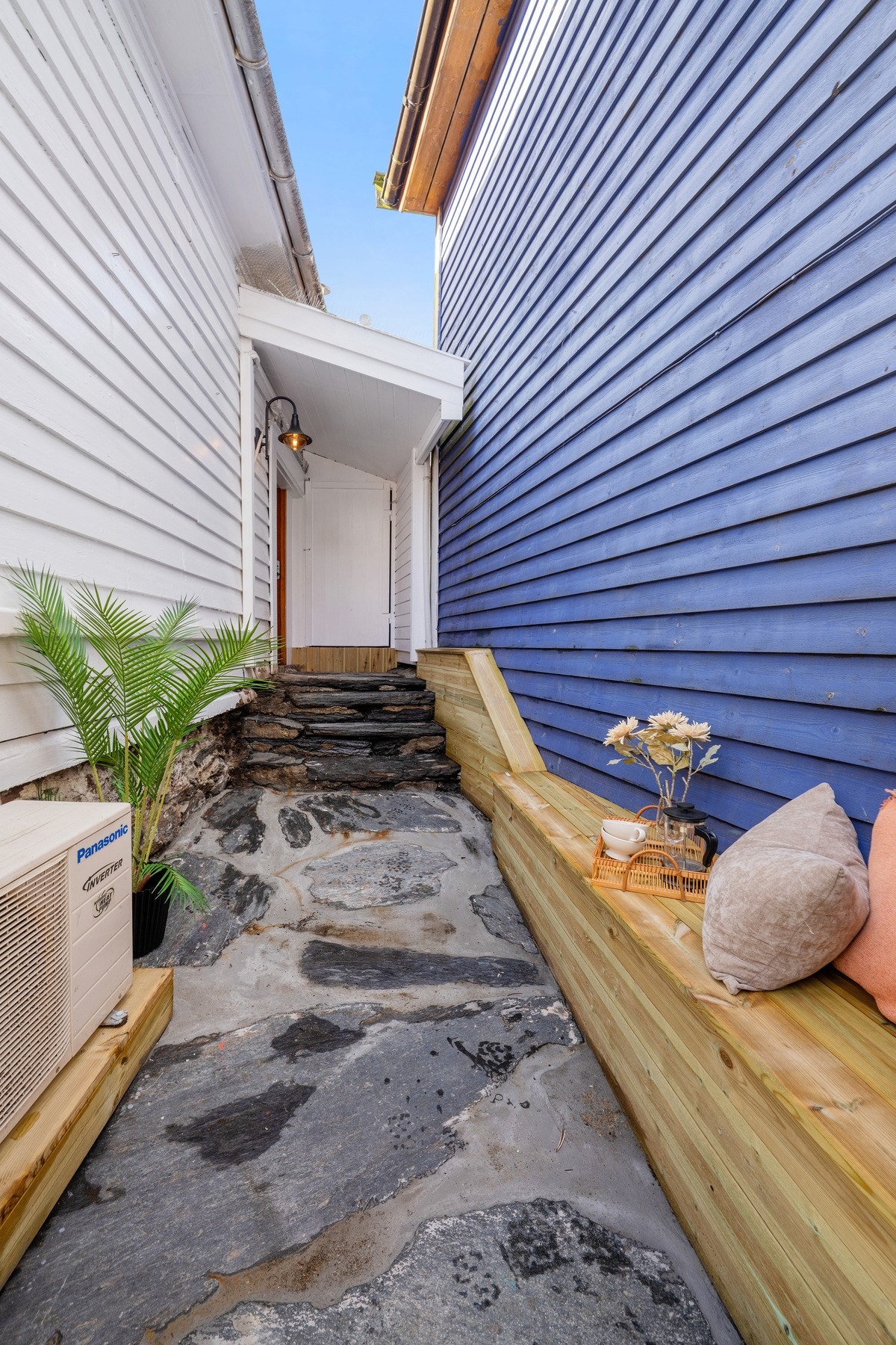 Huset har lukket utvendig inngangsparti med pene skifersteiner. Det er laget til en stedbygd benk og det er en praktisk bod i enden. Galleribilde