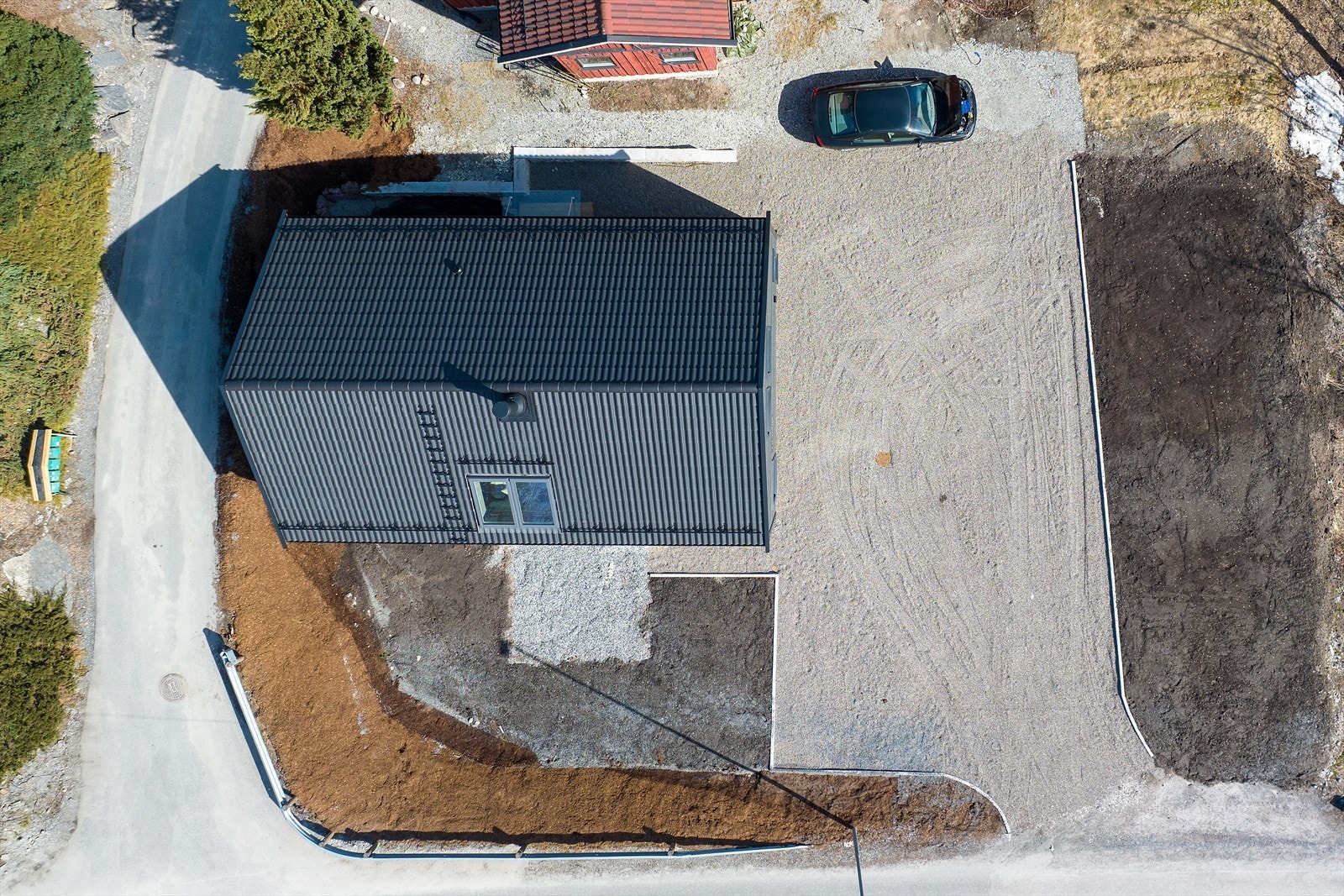 Tomten sett fra luften, med gruset gårdsplass og areal klargjort for hage. Galleribilde