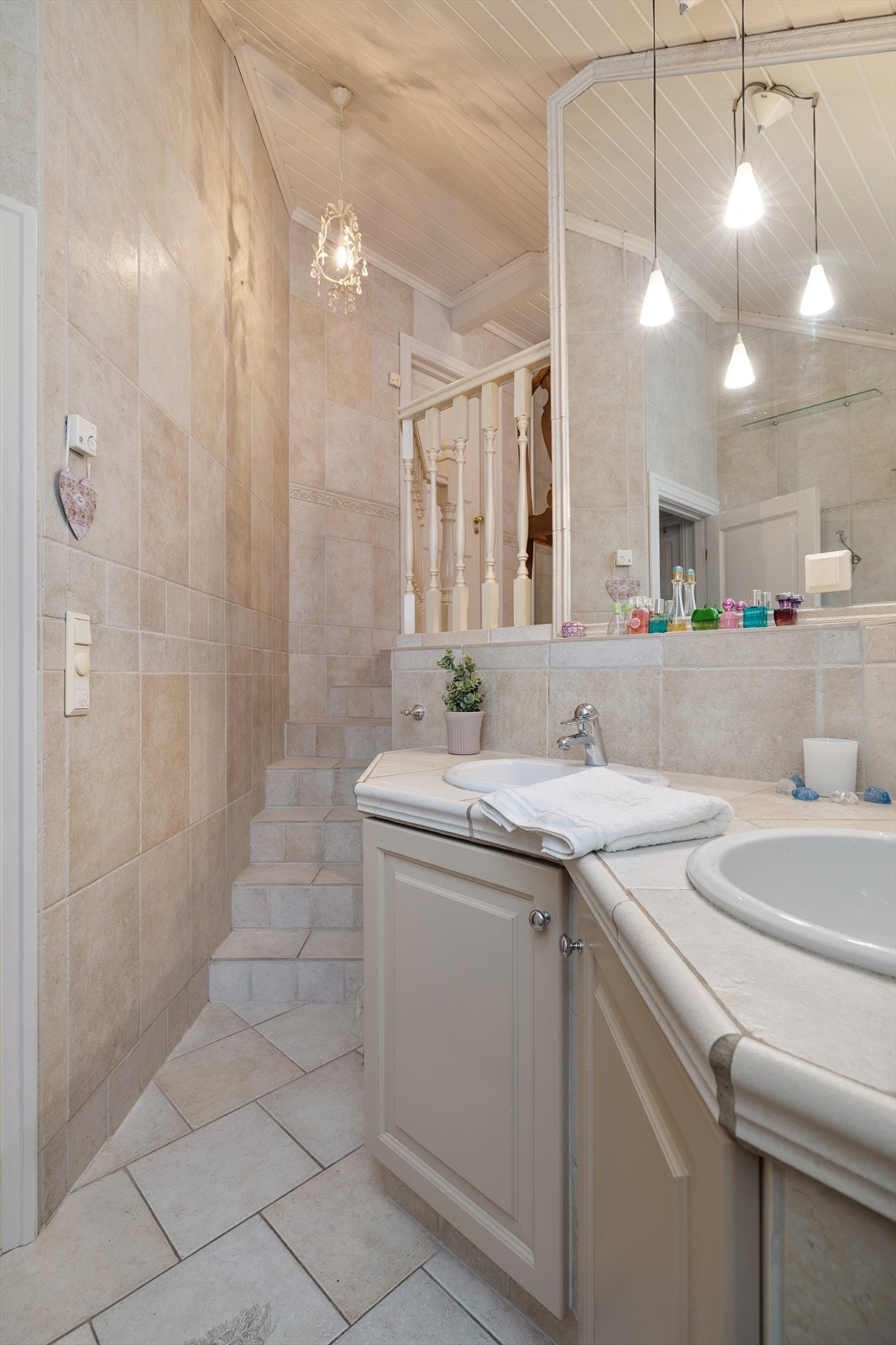 Hvis man beveger seg et halvetasje opp finner du hovedbadet som går over to nivåer. Badet har en lys og behagelig atmosfære med helflisede overflater i varme naturtoner. Galleribilde