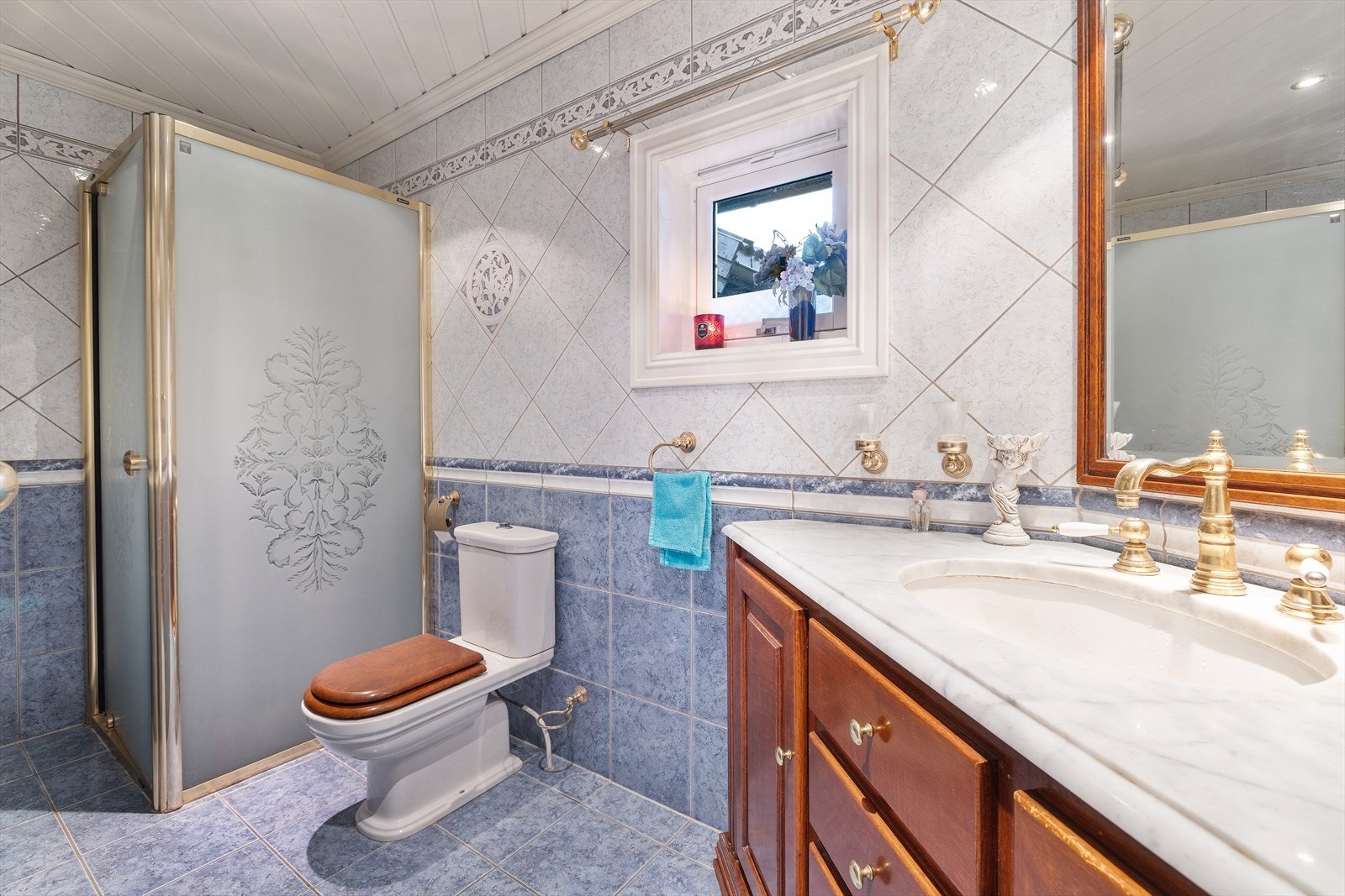 Messingdetaljer på armatur og tilbehør understreker den elegante stilen. Badet inneholder videre toalett og dusj hjørne med flotte detaljer. Galleribilde