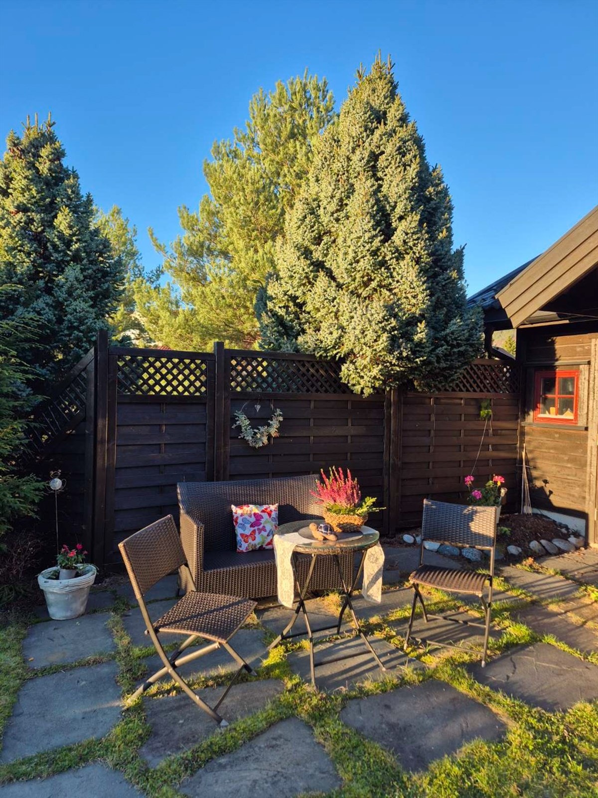 Uteområdet byr på en nydelig og privat ramme rundt boligen, omkranset av frodige busker, trær og natursteinsmurer som gir både skjerming og et harmonisk uttrykk. Galleribilde