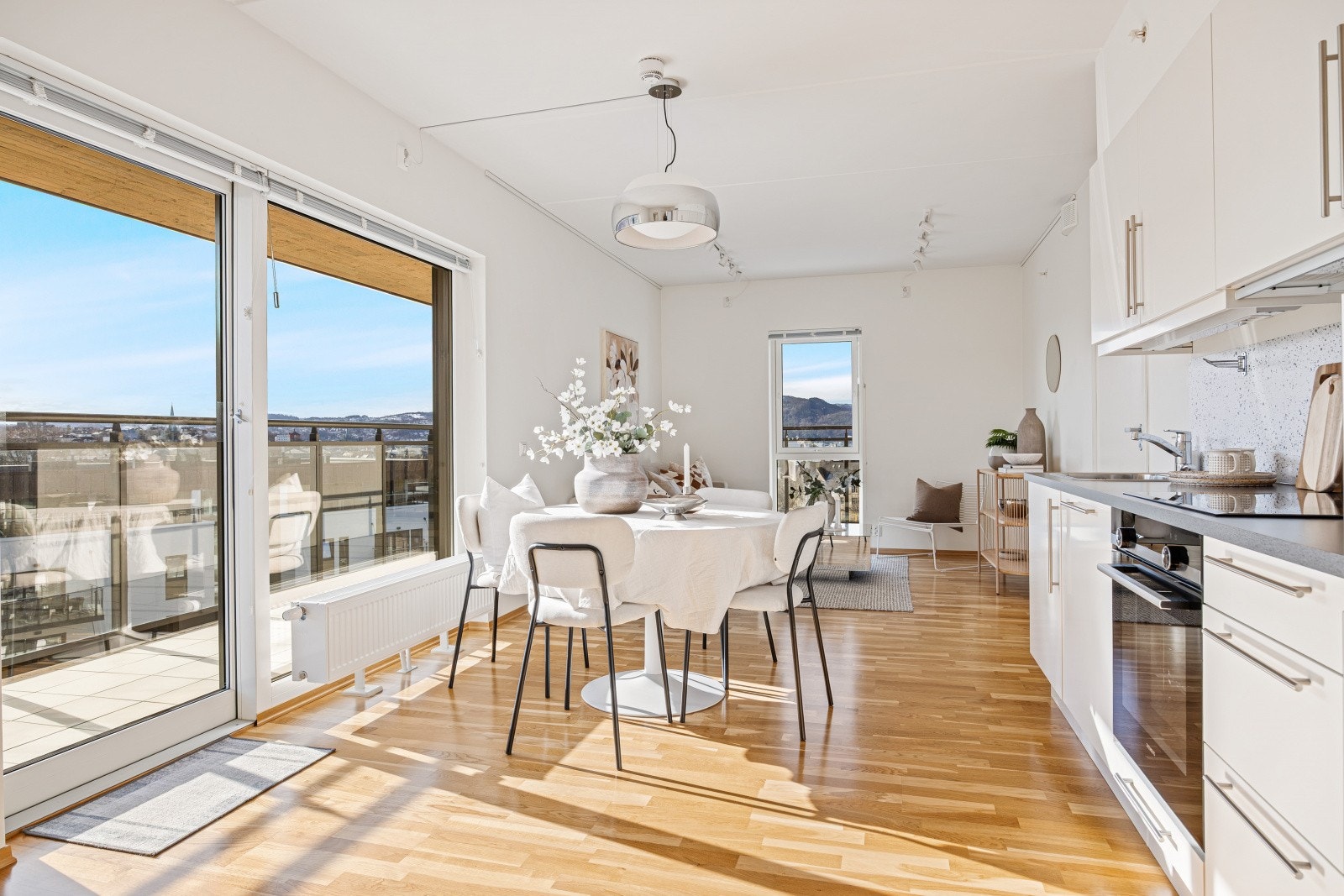 Den åpne stue- og kjøkkenløsningen er et meget hyggelig rom med store vindusflater som nærmest strekker seg fra gulv til tak. Plassbygde persienner gir god solskjerming på disse tre vinduene. Galleribilde