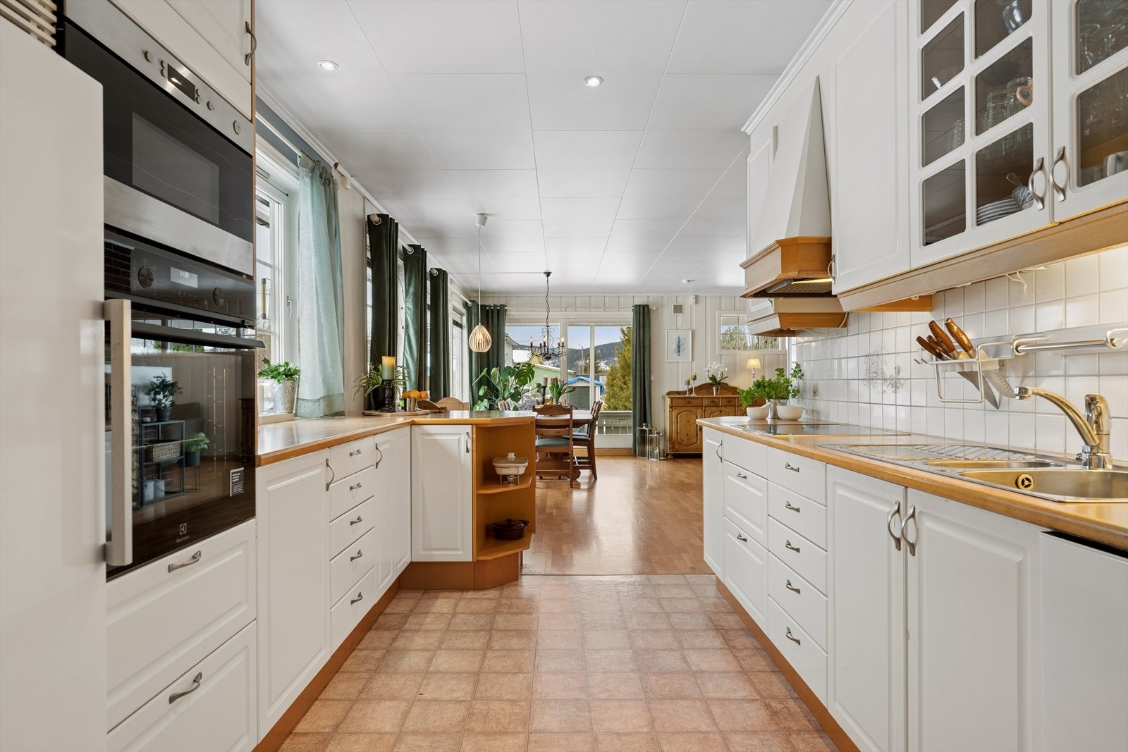 Innredning i heltre med profilerte fronter. Fliser over vask og platetopp. Galleribilde