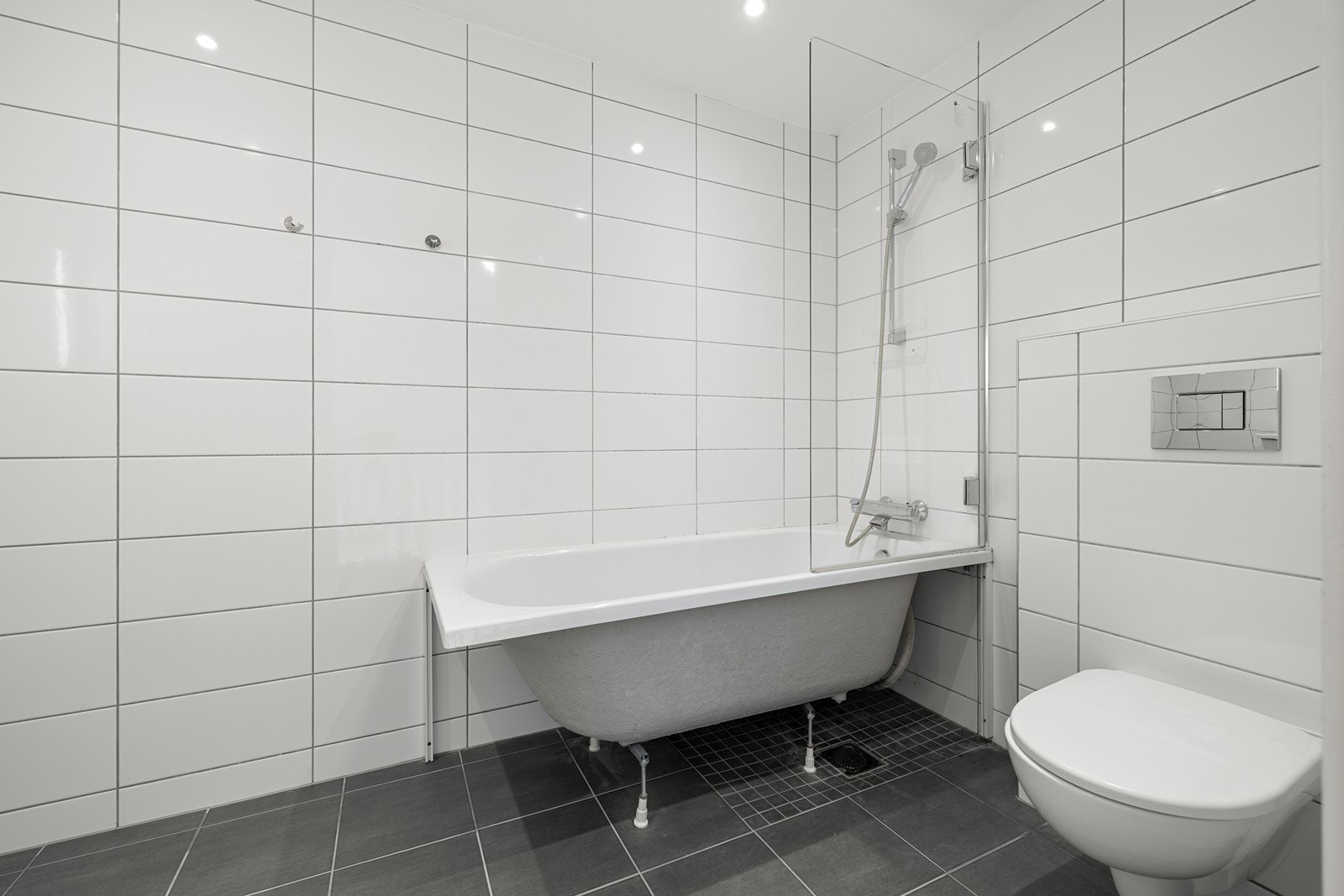 Badet innehar vegghengt toalett, servant med skuffer og badekar med dusjløsning. Galleribilde