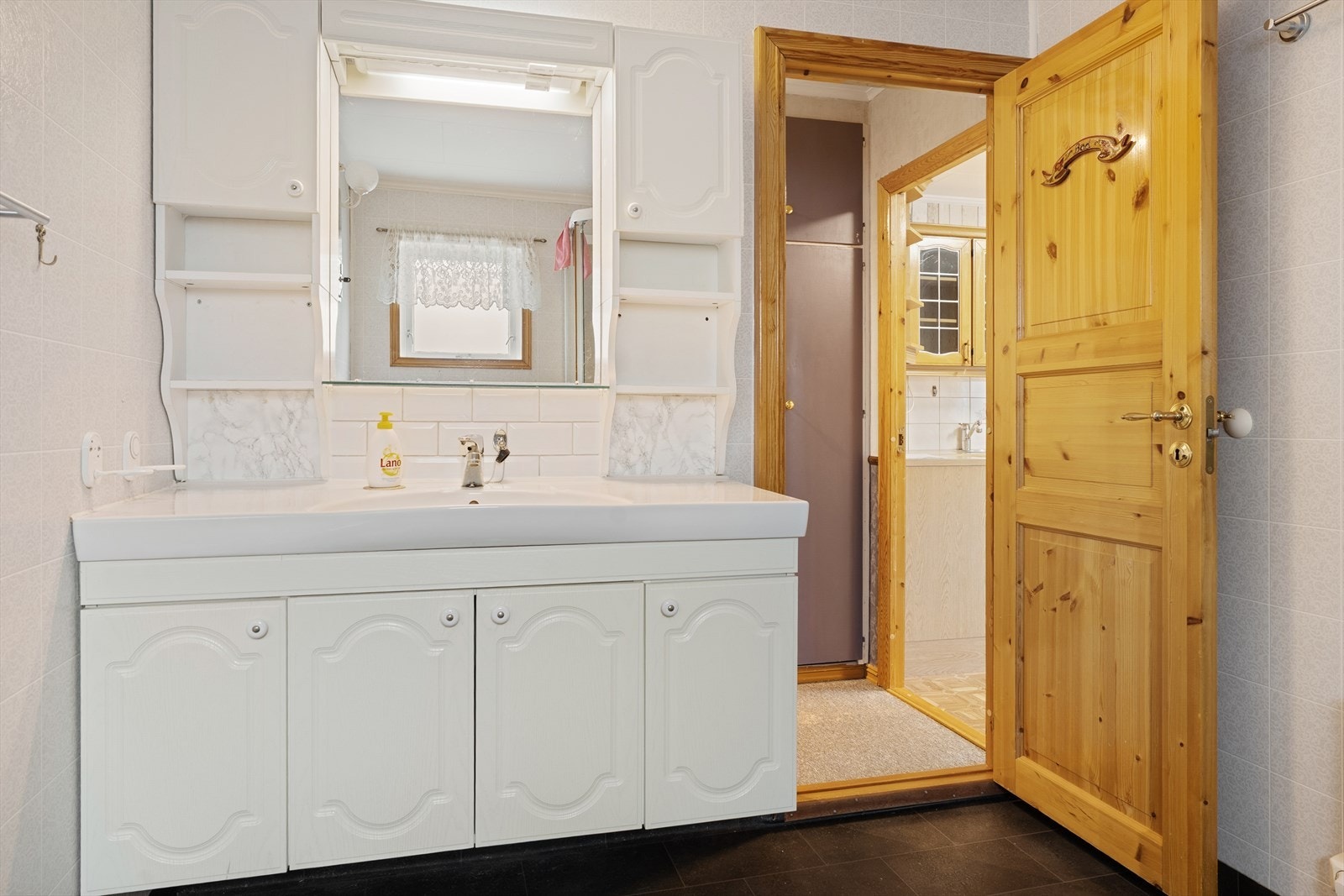 Badet er innredet med hvit baderomsinnredning, gulvmontert toalett og dusjkabinett Galleribilde