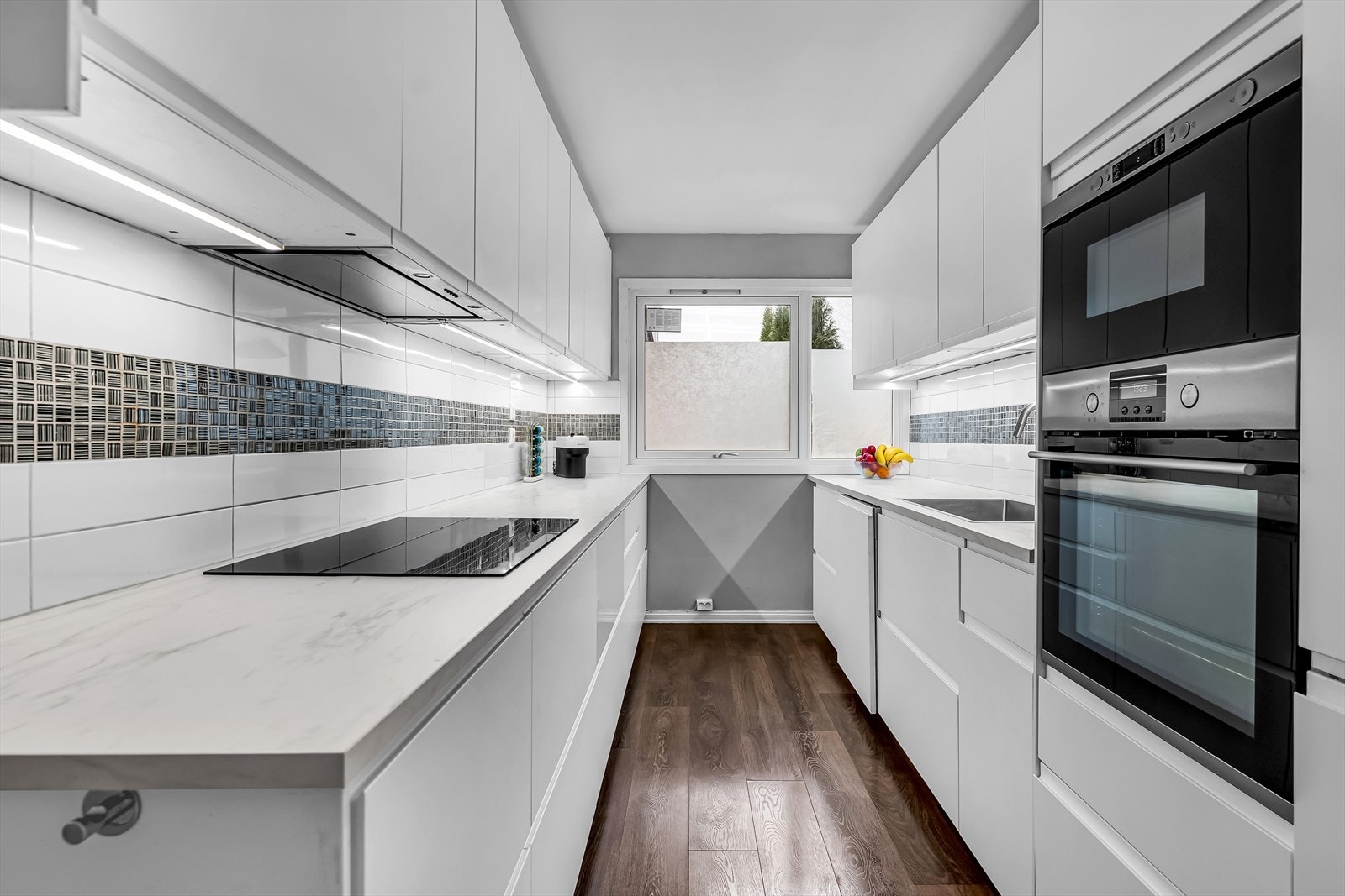 Moderne kjøkken fra IKEA med slette, lakkerte fronter, laminat benkeplate og flislagt bakvegg, som gir et stilrent og praktisk arbeidsområde. Galleribilde