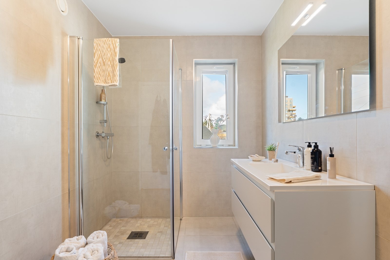 Lekkert, helfliset baderom med elektrisk varmekabel i gulvet. Rommet har innredning med heldekkende servant, veggmontert toalett og dusjvegger/hjørne. Galleribilde