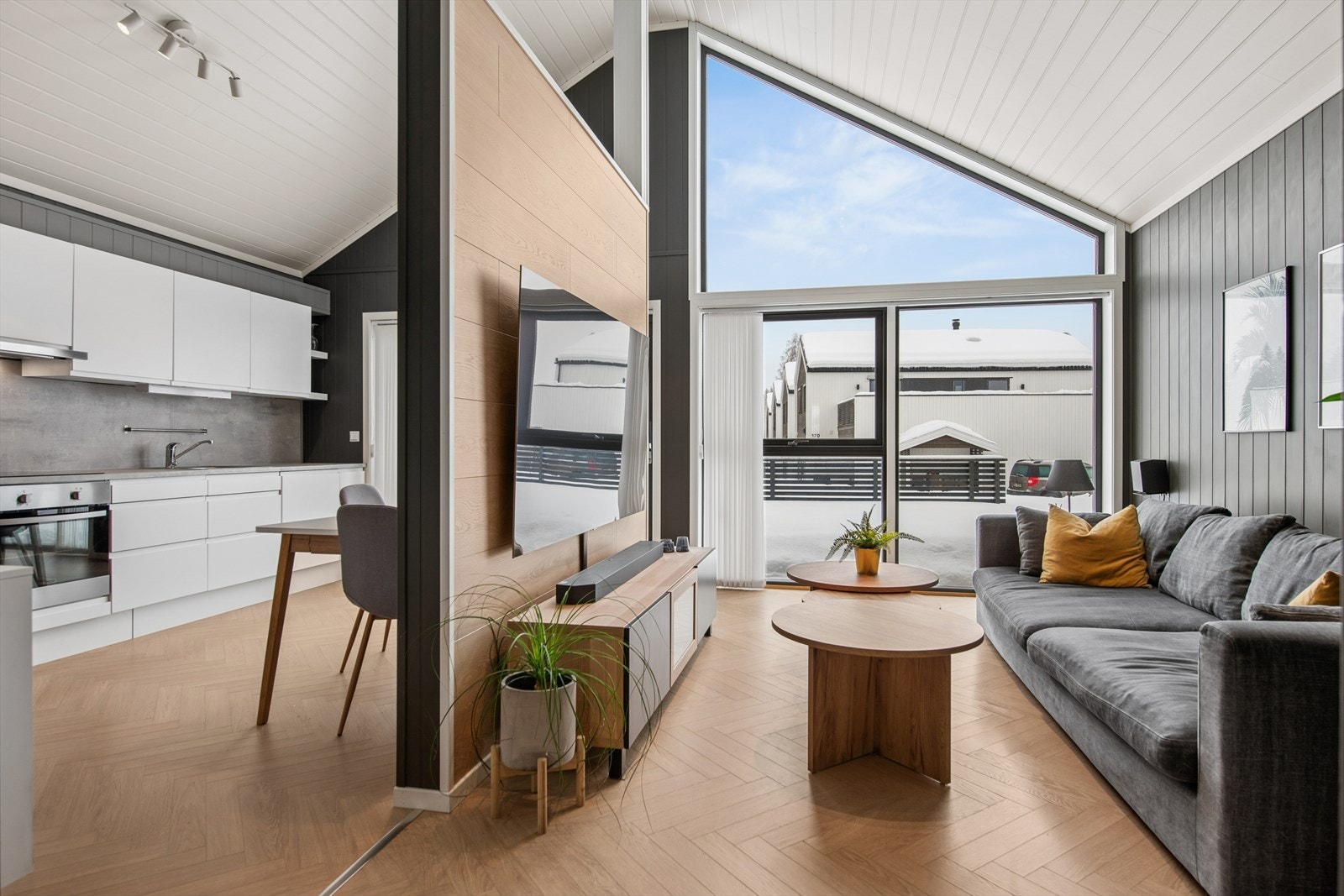 Åpen stue- og kjøkkenløsning med store vindusflater og god takhøyde som gir en luftig atmosfære. Galleribilde