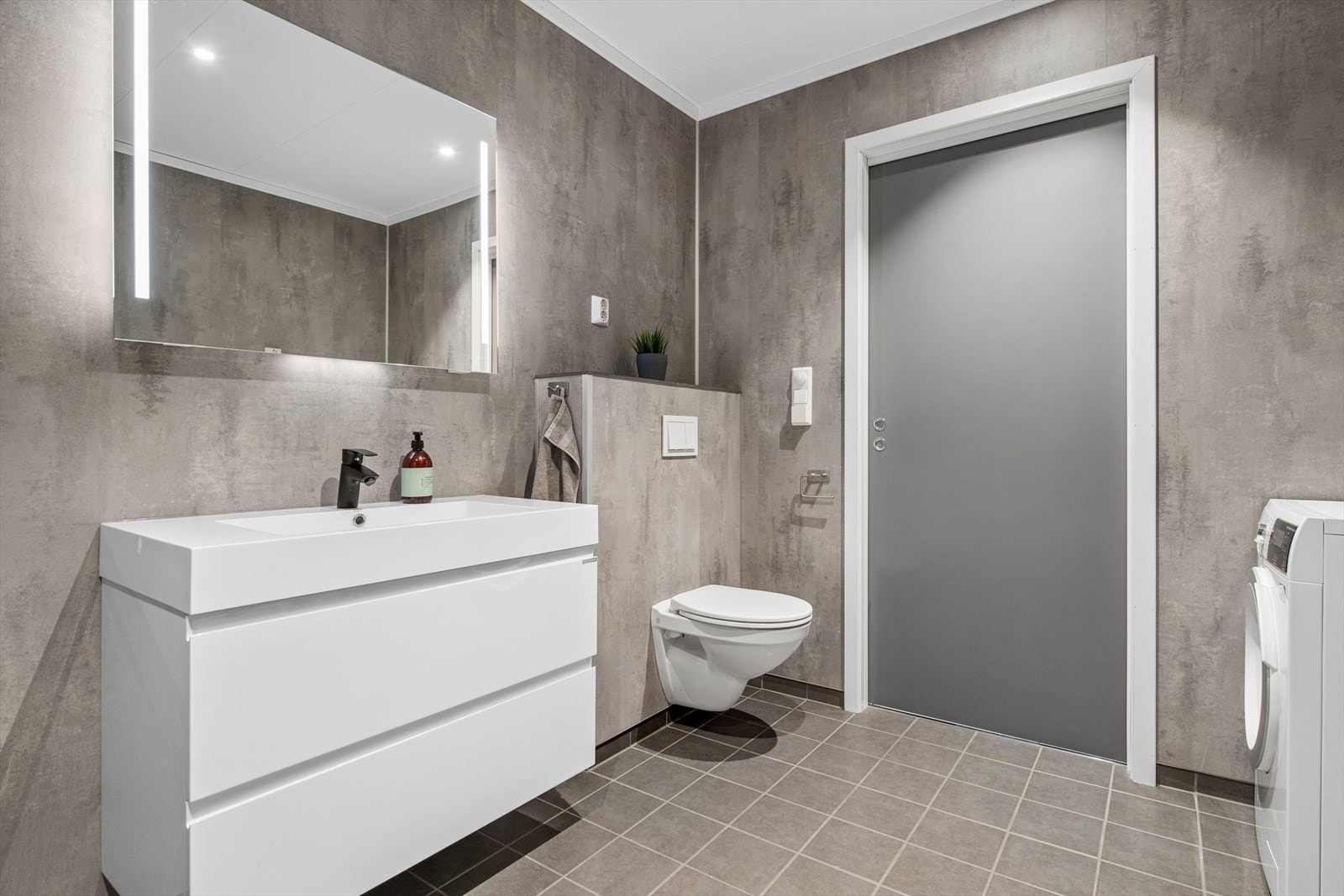 Baderomsinnredningen består av servant med underskap, speil med integrert belysning og vegghengt toalett. Galleribilde