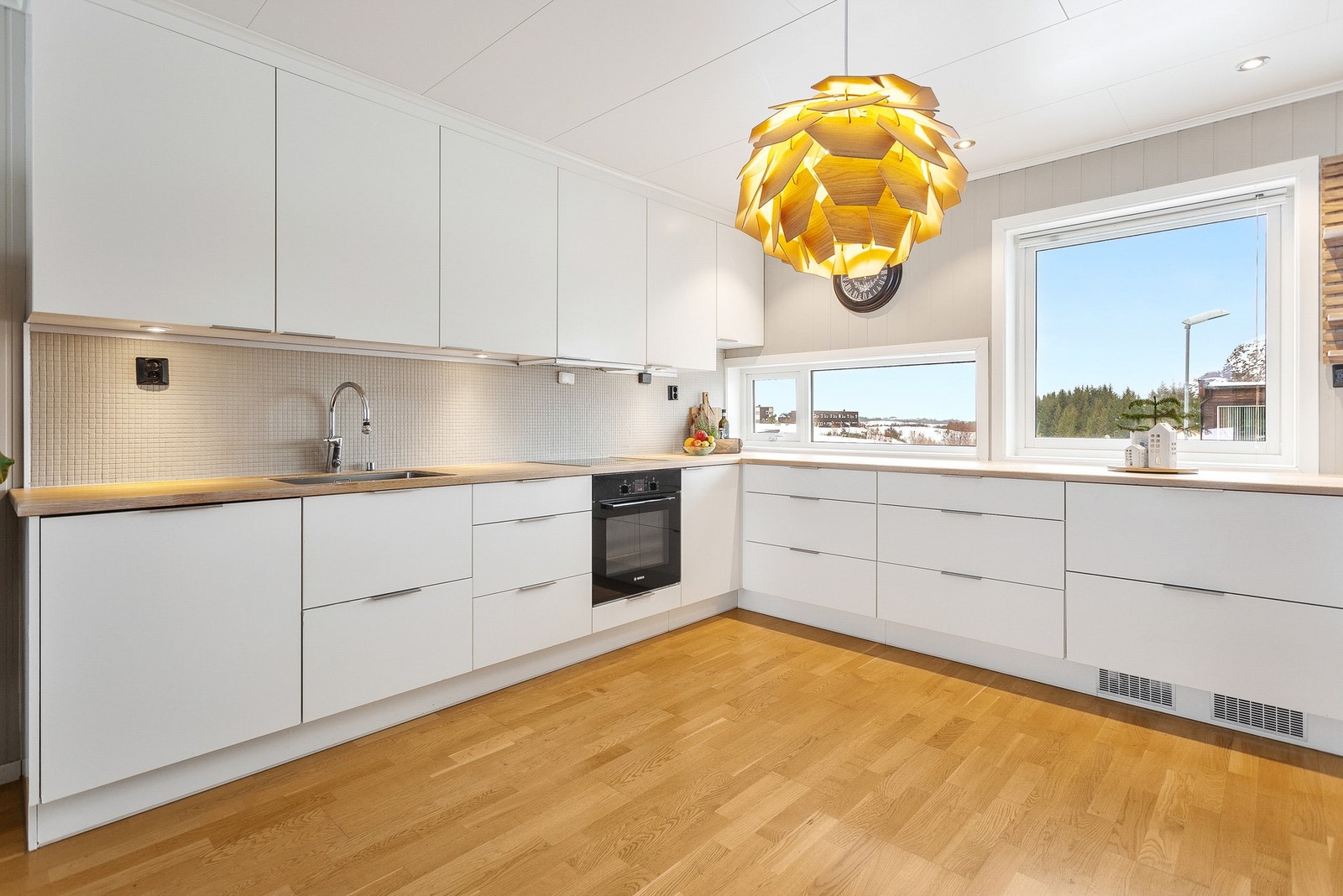 Moderne kjøkkeninnredning med integrert stekeovn, platetopp, kjøleskuffer og oppvaskmaskin. Galleribilde