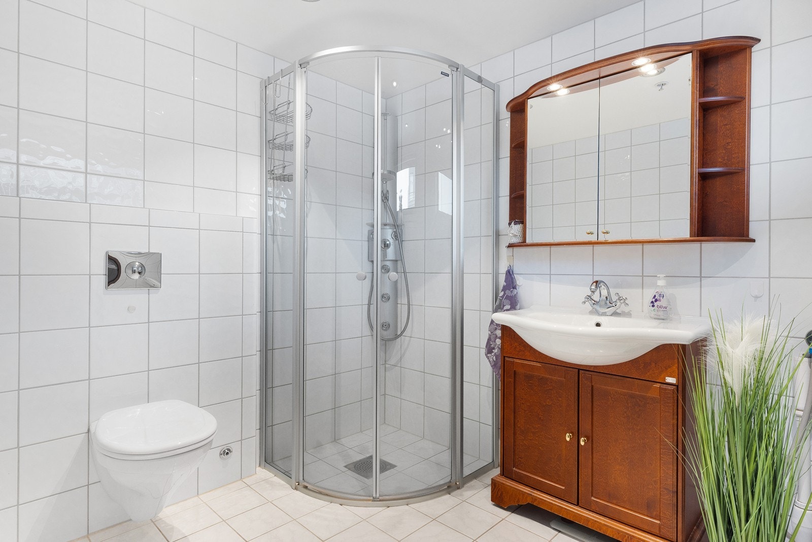 Helfliset baderom som inneholder pen innredning, hjørnedusj og vegghengt toalett. Galleribilde