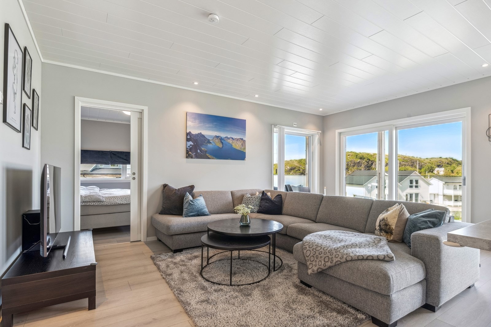 Stue med mye glass og utsikt over fjorden og båthavn. Skyvedør til soverom. Galleribilde