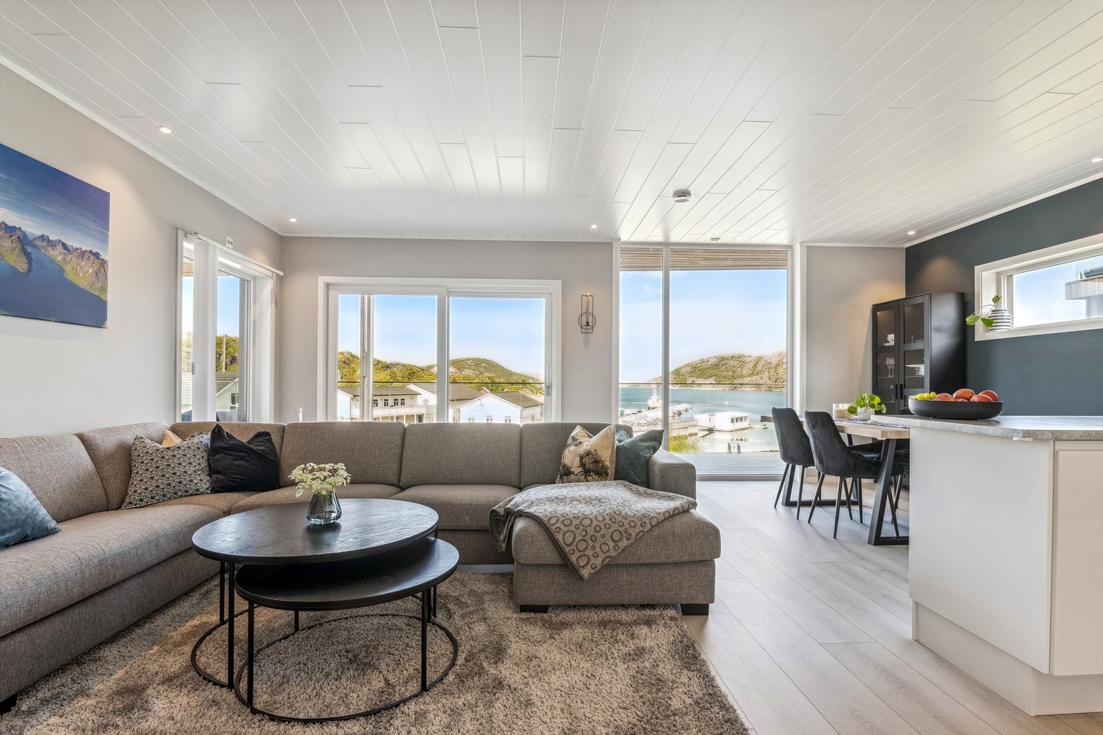 Stue med mye glass og utsikt over fjorden og båthavn Galleribilde