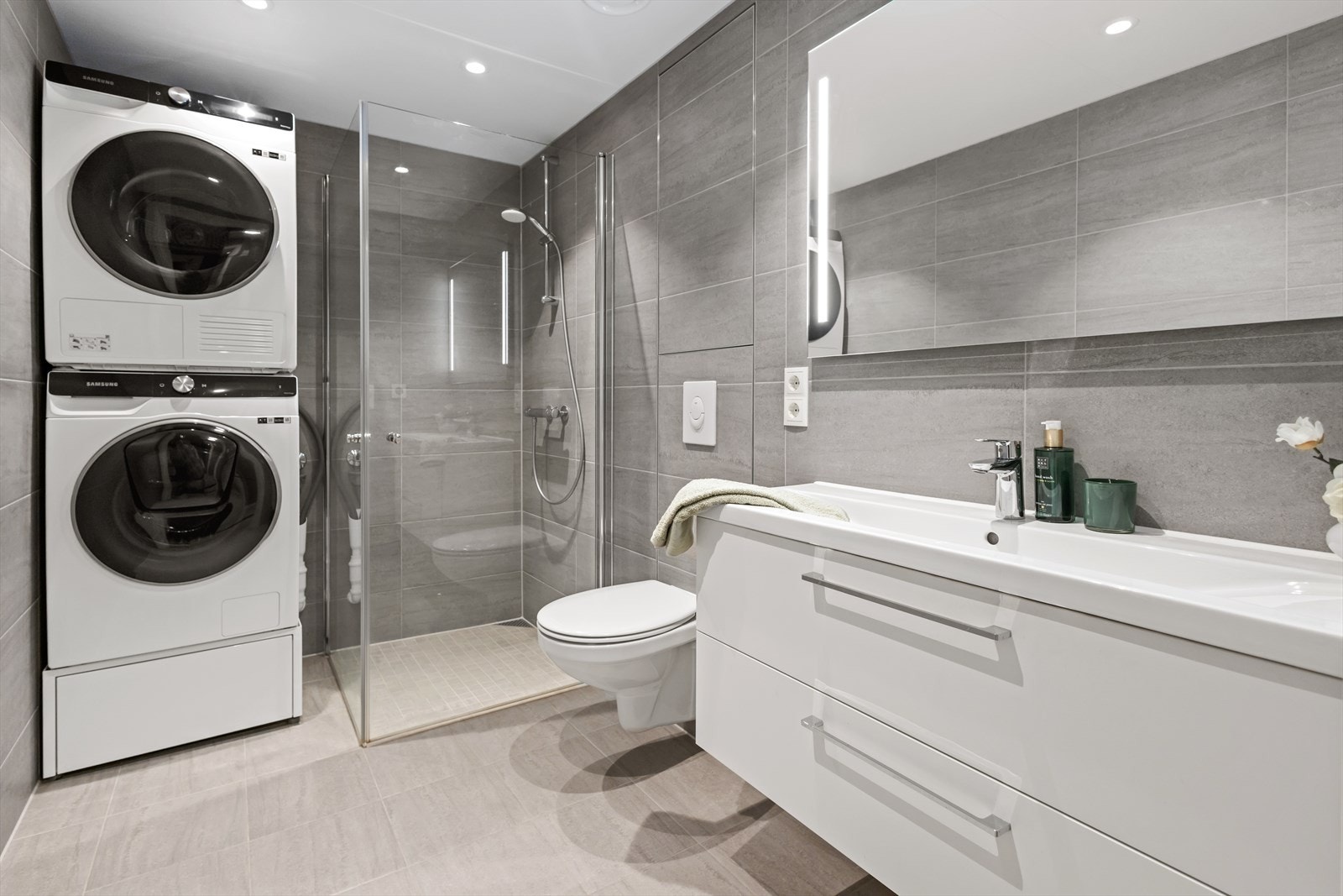 Innredning bestående av servantskap i hvit glatt utførelse
med heldekkende servant, speil med integrert
ledlys, vegghengt wc og dusjnisje. Galleribilde