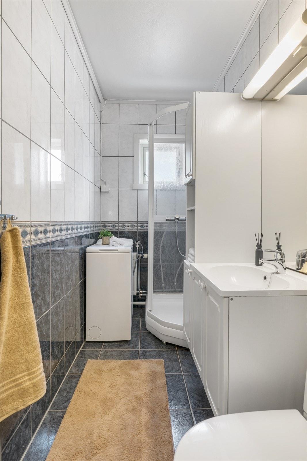 Flislagt og lettstelt bad med dusjkabinett og opplegg til vaskemaskin. Galleribilde