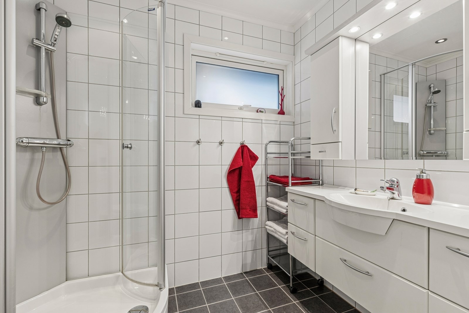 Badet ligger i boligens 1.etg og er utstyrt med dusjkabinett, servant med skap, speil med oppbevaring på sidene og toalett. Galleribilde