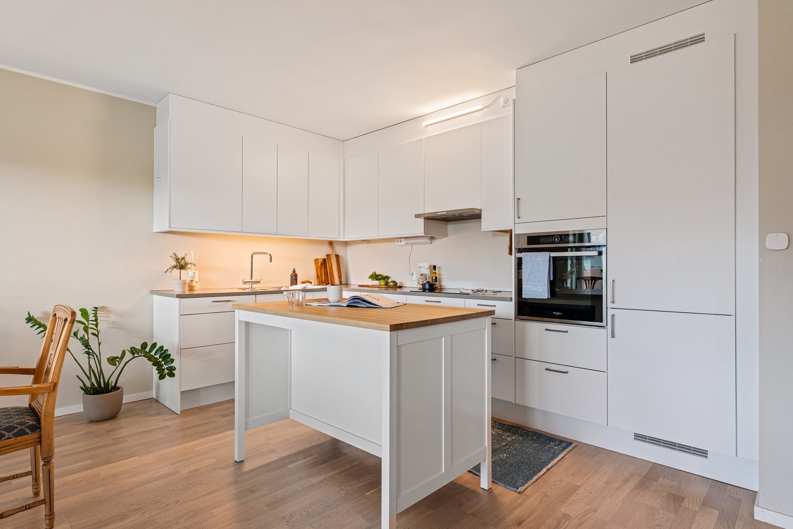 Kjøkkenet er innredet med høyskap, integrerte hvitevarer og benkeplate av laminat Galleribilde