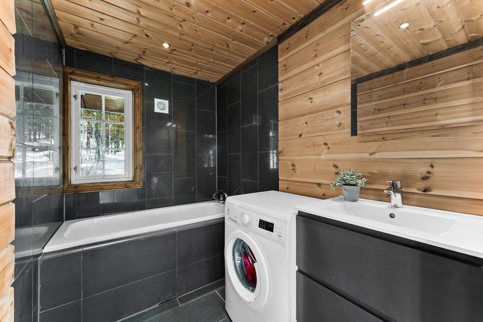 Det andre badet har tilsvarende praktiske løsninger med flislagt gulv med varme, badekar og opplegg for vaskemaskin. Galleribilde