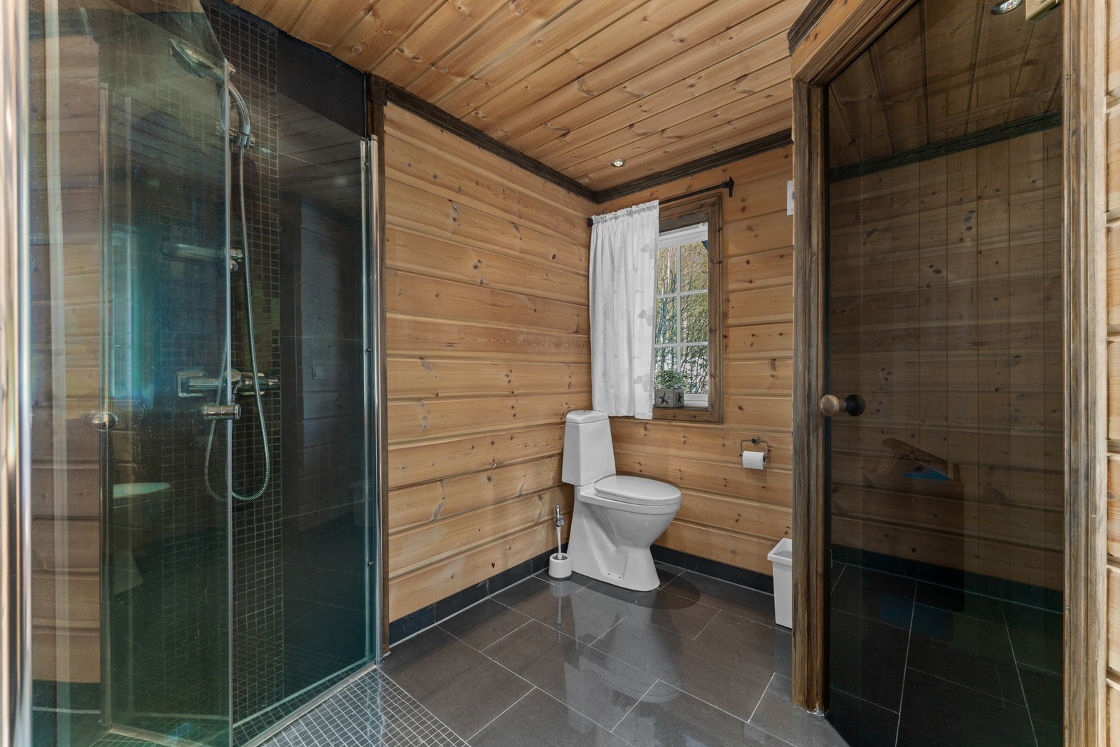 Det ene badet har tilknytning til badstue - perfekt etter lange dager ute. Her er det flislagt gulv med varme, fliser i dusjsonen og panel på øvrige flater, samt moderne innredning med servant, dusjdører og toalett. Galleribilde