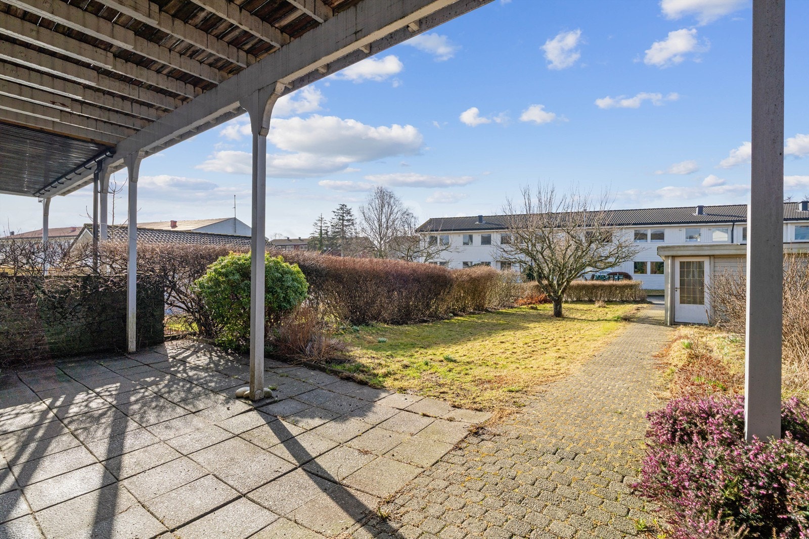 Den skjermede hagen har en hellelagt uteplass og gressplen. Galleribilde