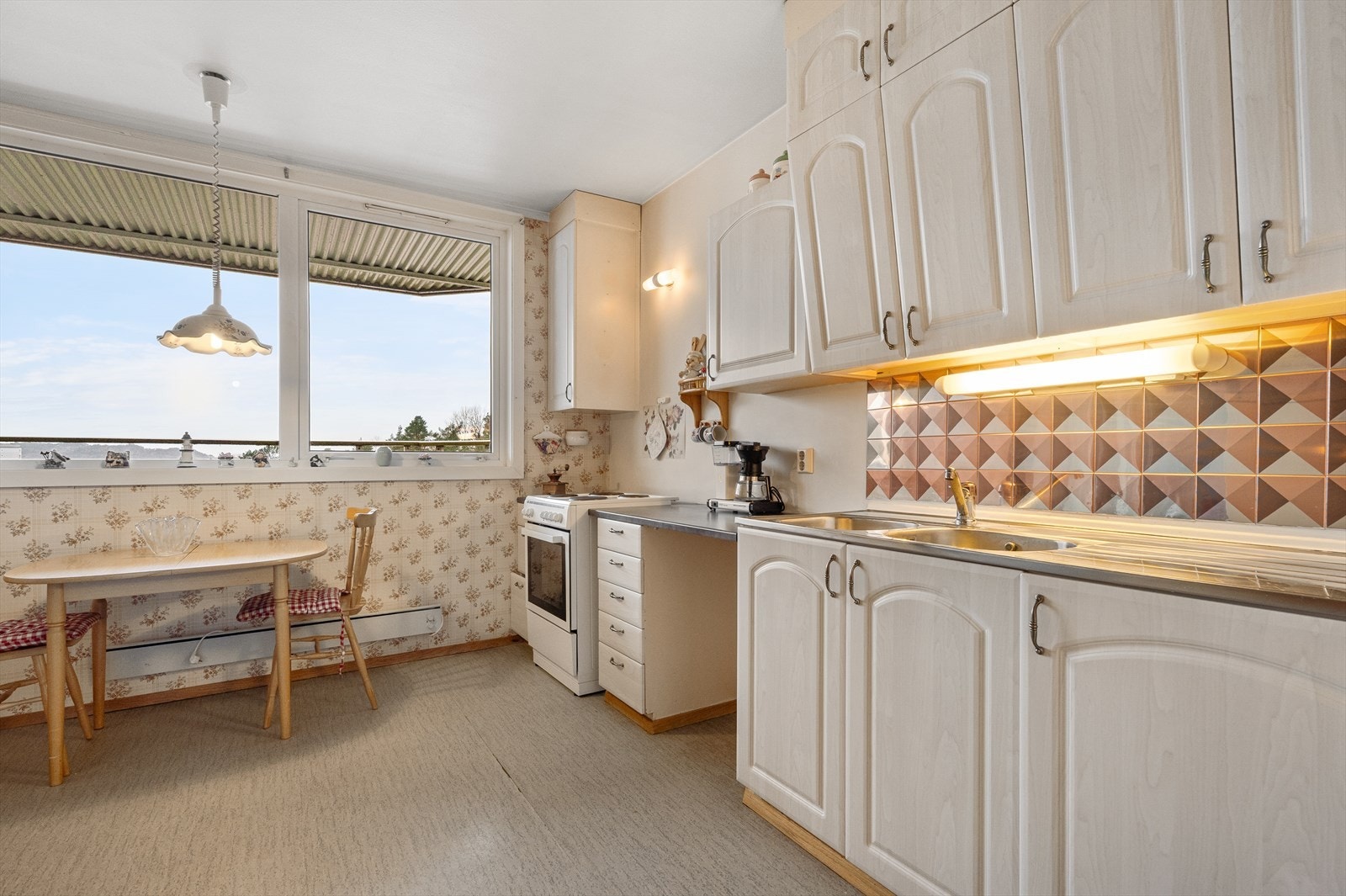 Det er laminat benkeplate og lysarmatur med stikkontakt under overskap Galleribilde