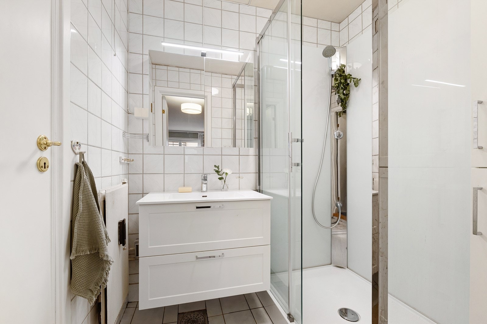 Innredningen består av heldekkende servant med nedfelt vask, praktisk baderomsinnredning med skuffer, speilskap, dusjkabinett med skyvedører samt vegghengt skap for ekstra oppbevaring. Galleribilde