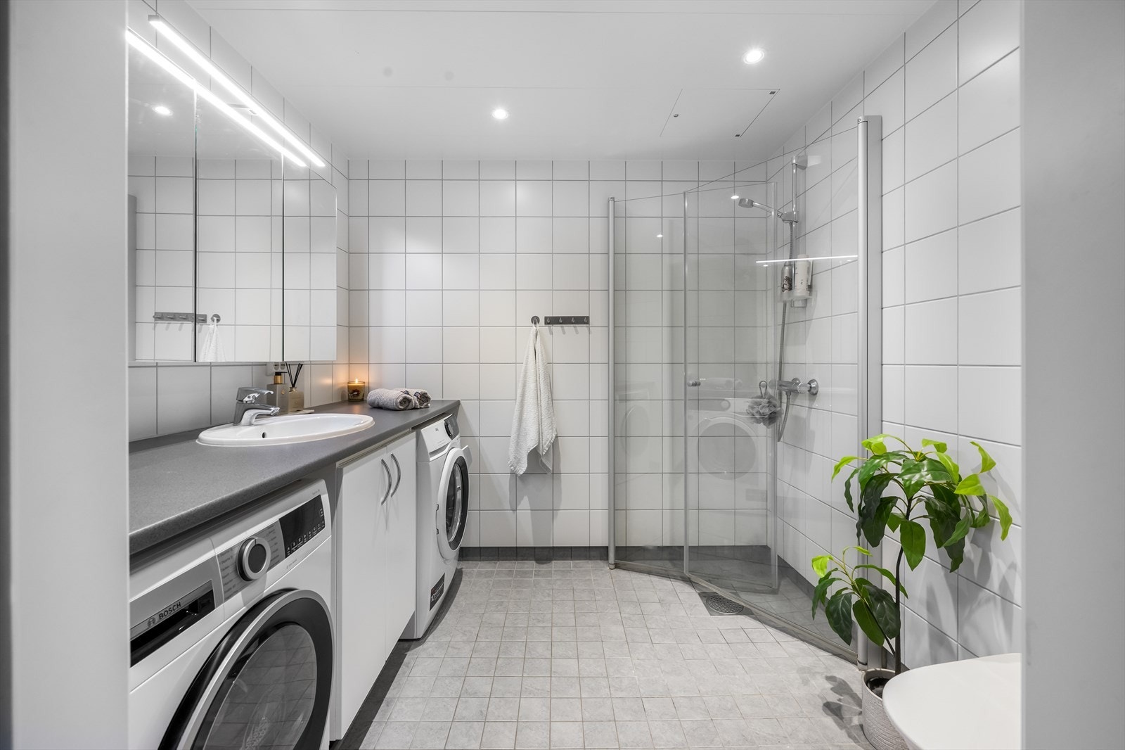 Flislagt bad med vannbåren gulvvarme, dusjhjørne med innsvingbare glassdører og opplegg for vaskemaskin. Galleribilde