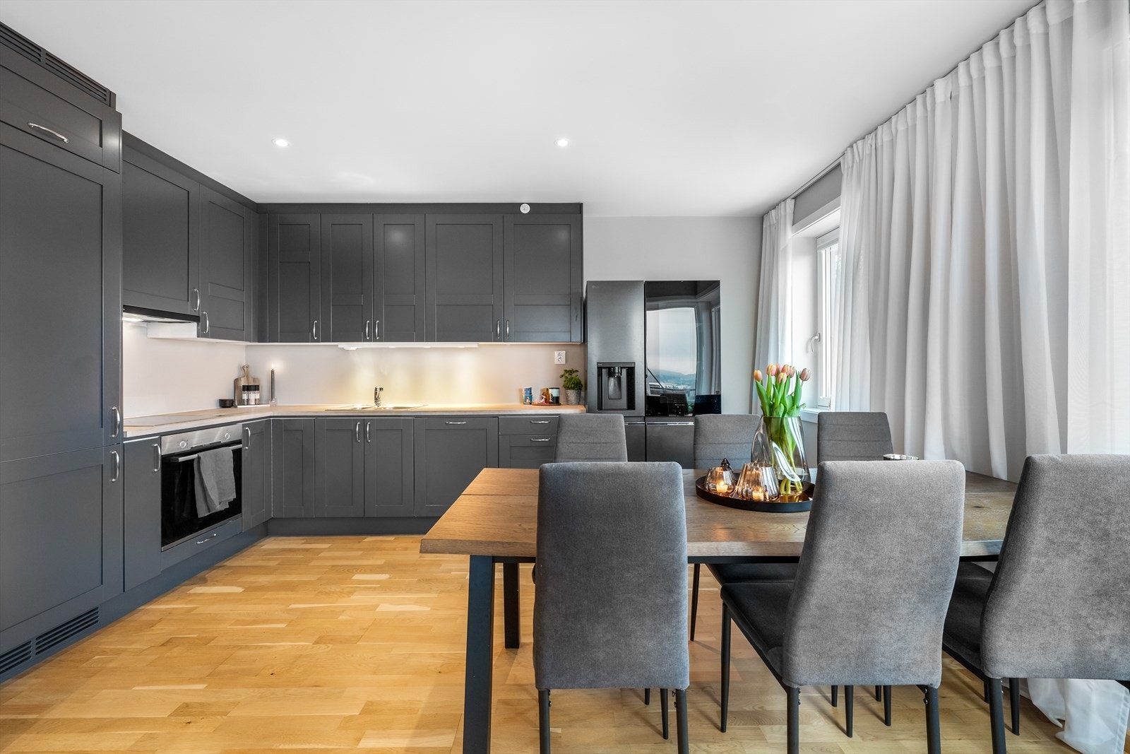 Kjøkkeninnredning med profilerte fronter og benkeplate i heltre. Hvitevarer som platetopp, stekeovn og oppvaskmaskin er integrert. Galleribilde