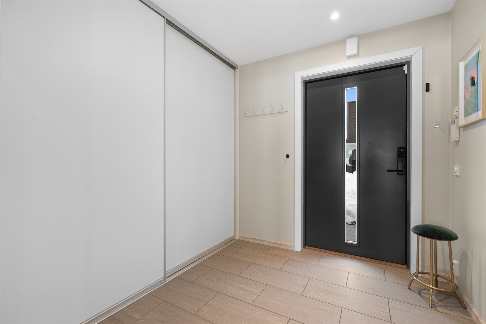 Entré med flislagte gulv med varme og god plass til å henge fra seg yttertøy i praktisk skyvedørsgarderobe Galleribilde