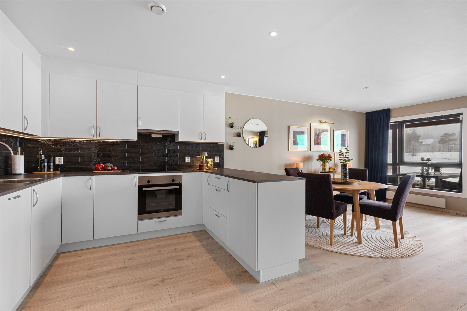 Kjøkkenet er flislagt mellom kjøkkenbenk og overskap. Benkeskapsbelysning under overskap. Integrerte komfyr med nedfelt induksjonstopp. Galleribilde