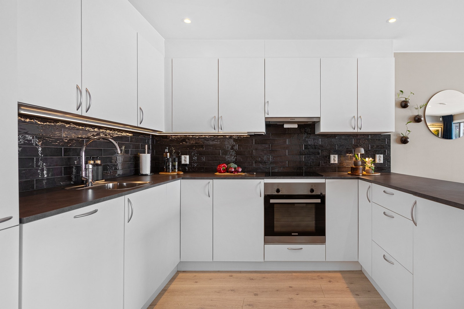 Kjøkkeninnredning med hvite glatte fronter fra byggeår. Benkeplater av laminat. Nedfelt oppvaskkum med ett-greps armatur Galleribilde