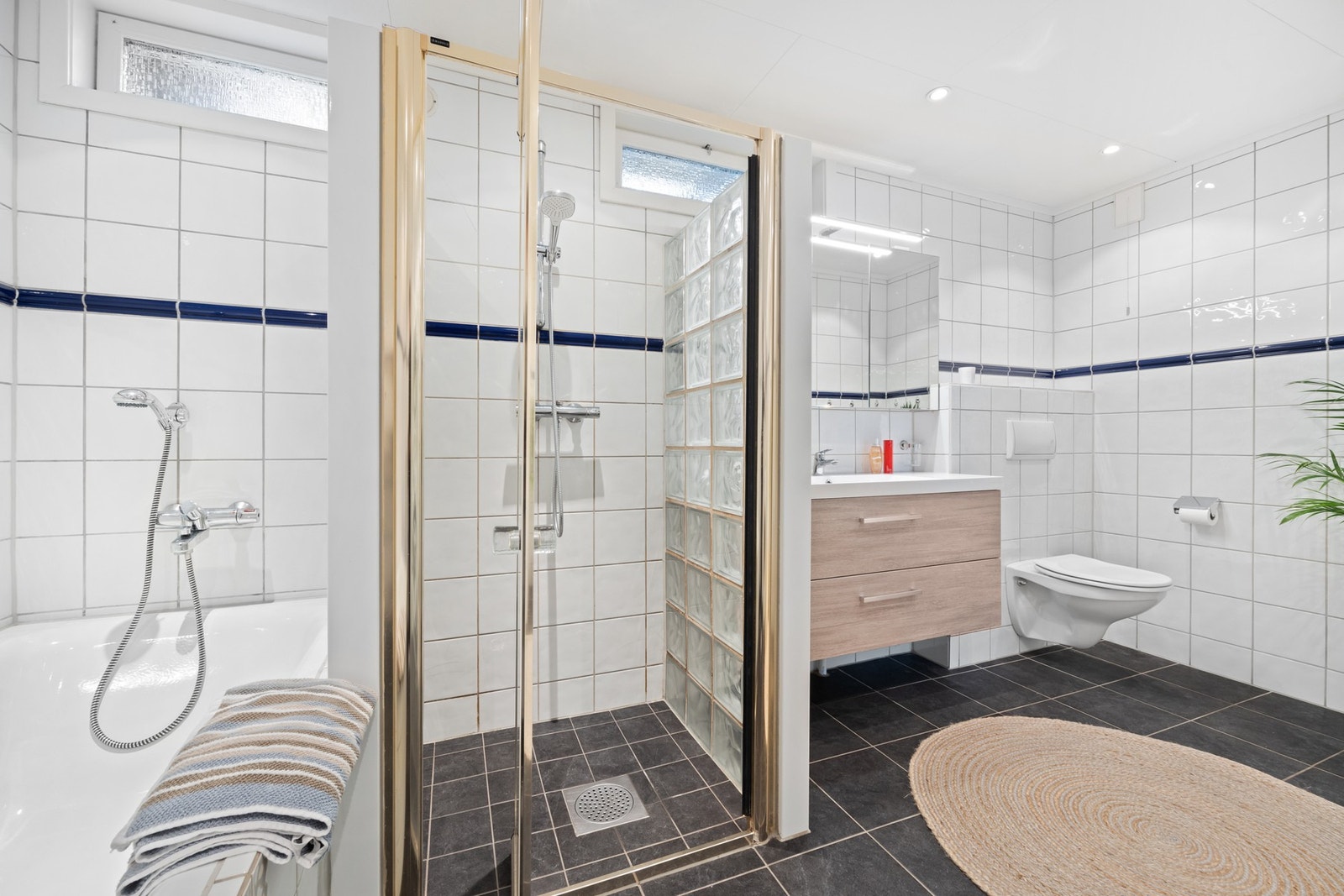 Stort bad i midtre plan med bl.a. toalett, dusj og badekar samt opplegg for vaskemaskin og tørketrommel. I tillegg er det et separat toalettrom i rommet ved siden av. Galleribilde