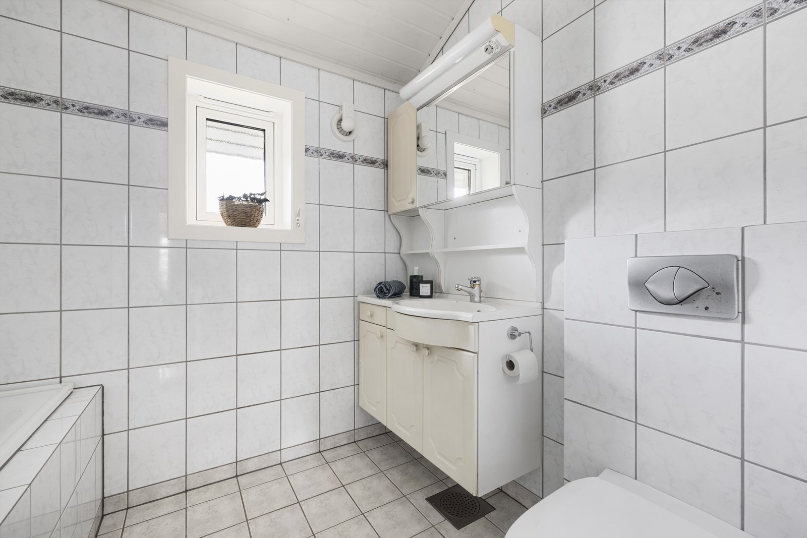 Badet er utstyrt med vegghengt wc, badekar med dusj på vegg, innredning ,ed vask, speilskap og sideskap. Galleribilde