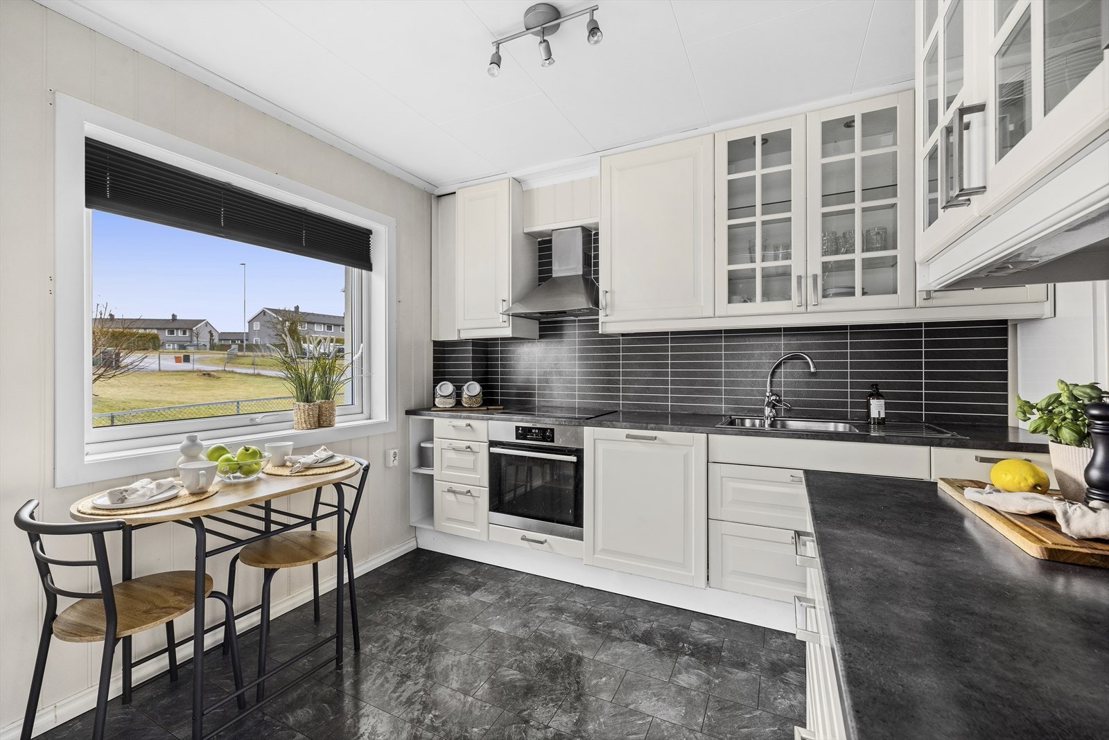 Kjøkkeninnredning med profilerte fronter og laminert benkeplate. Praktiske plater på vegg mellom kjøkkenbenk og overskap. Galleribilde