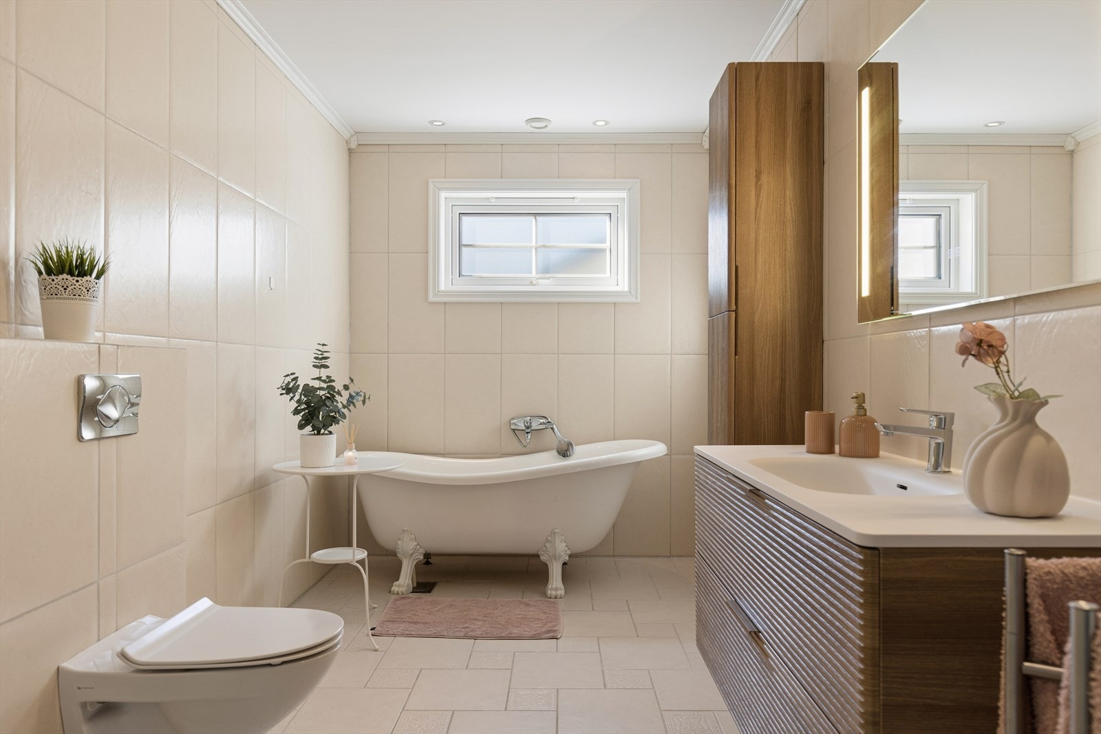 Badet er utstyrt med badkar, dusjhjørne, vegghengt toalett og en moderne baderomsinnredning. Galleribilde