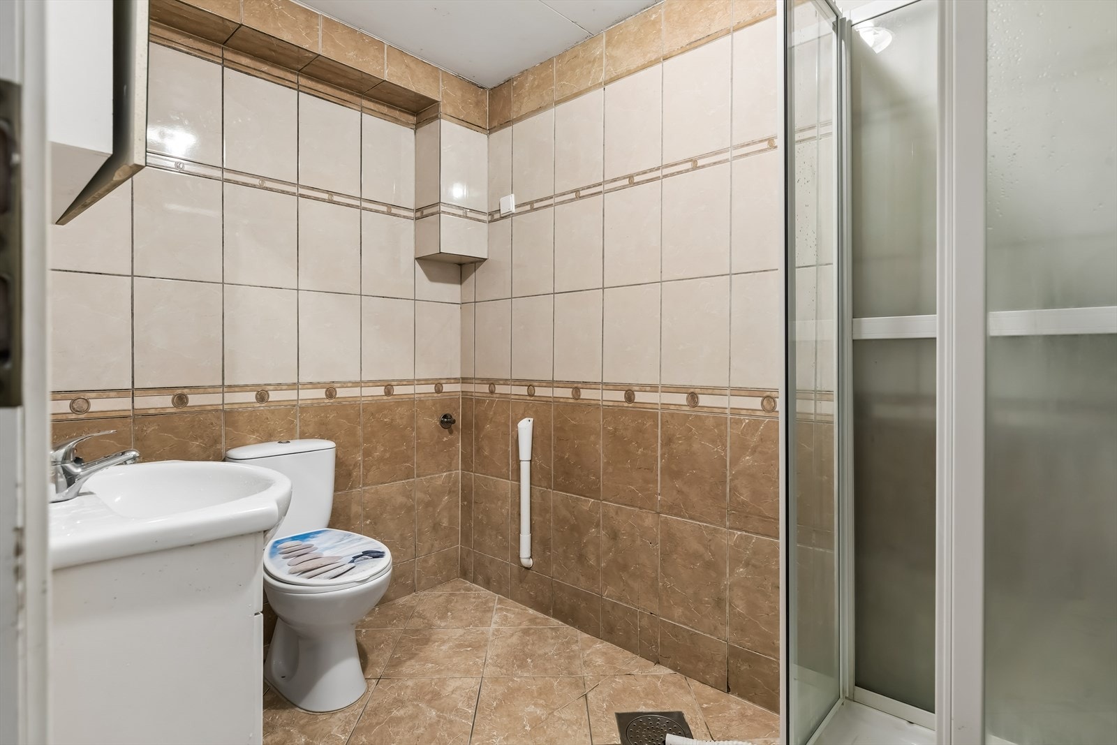 Badet i kjellerleiligheten har dusjkabinett og varme i gulv, men er av eldre dato med behov for totalrenovering. Galleribilde