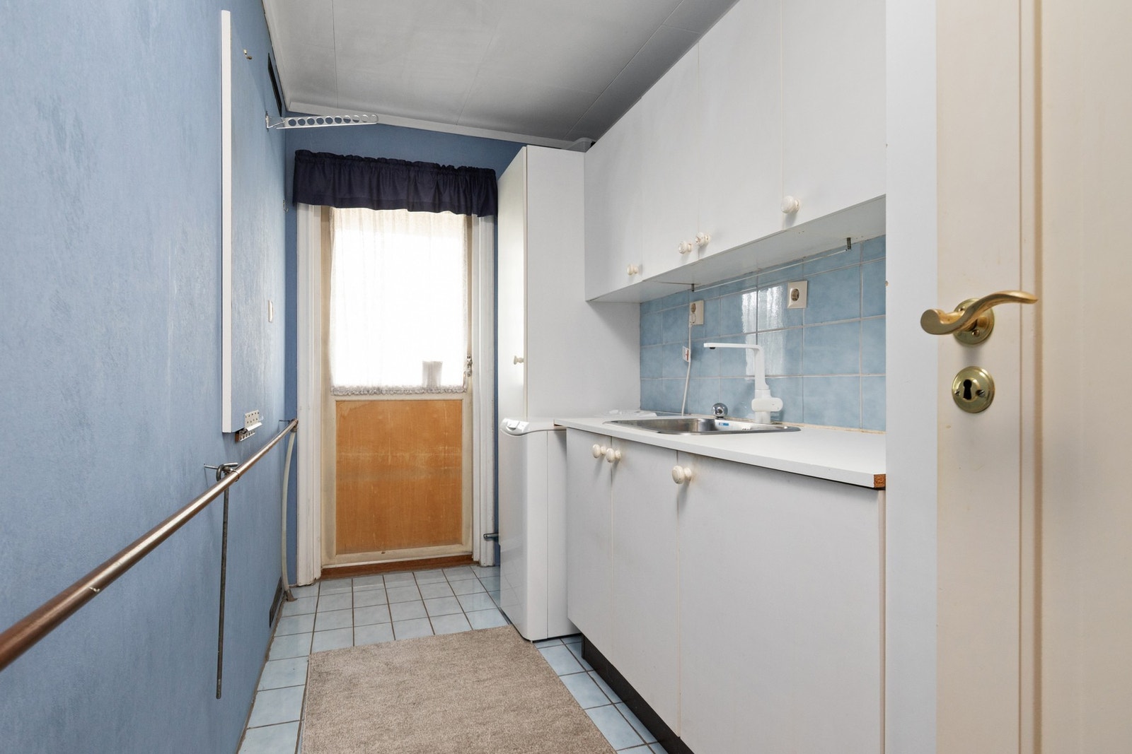 Vaskerom med fliser på gulv og tapet på vegger.
Innredning med benk og skap. Opplegg for vaskemaskin. Galleribilde