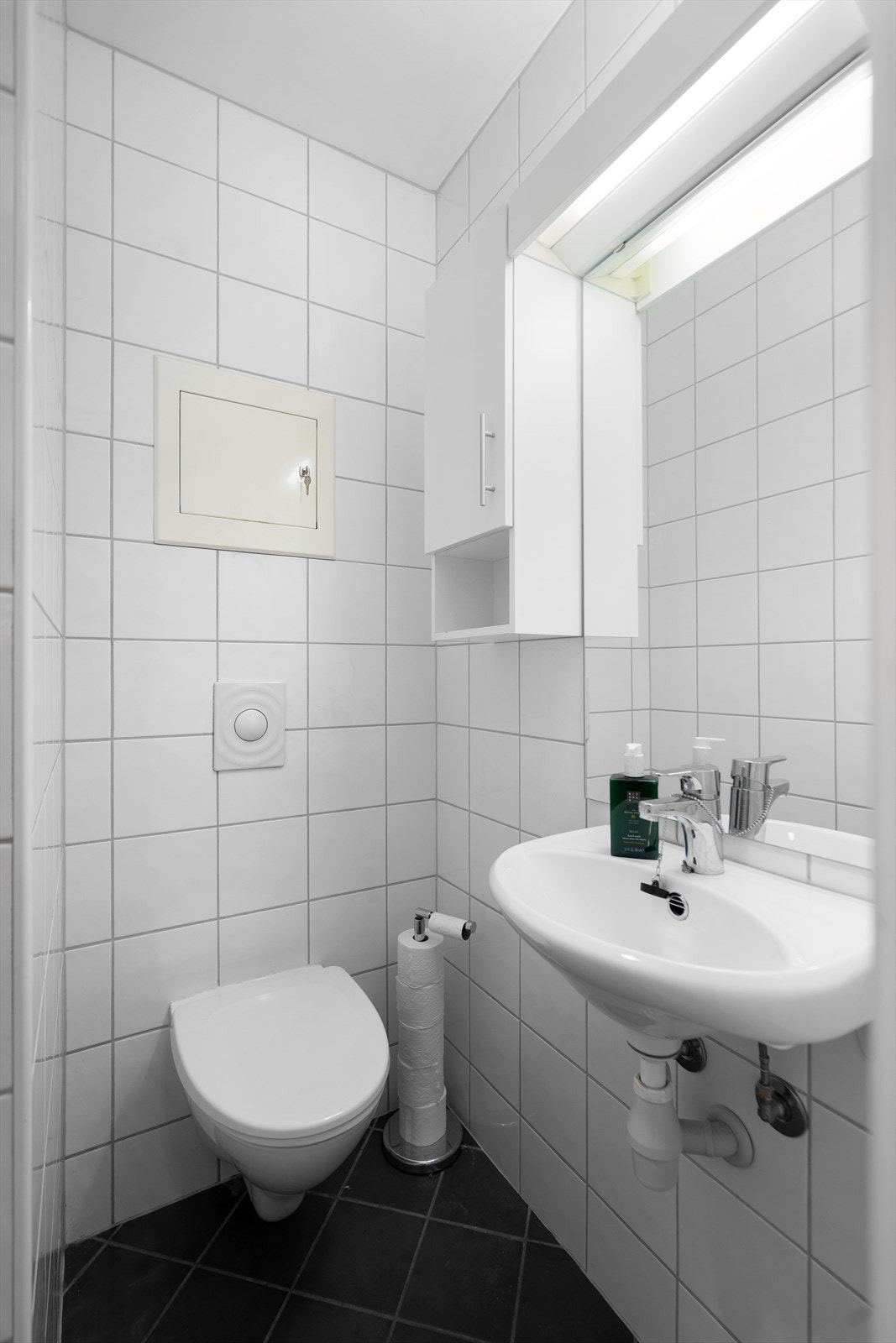 Flislagt bad i 1. etasje med vegghengt toalett, dusj og servant Galleribilde